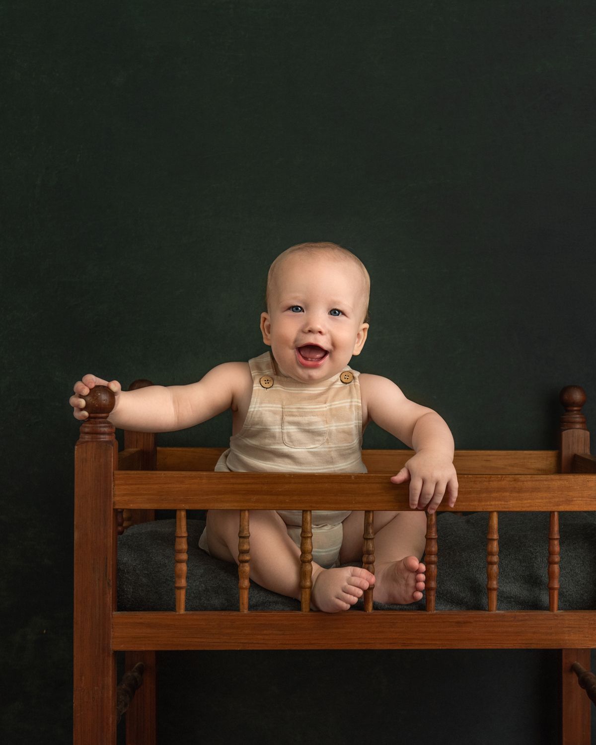Wooden crib railing photographed against dark background in classic portrait style.