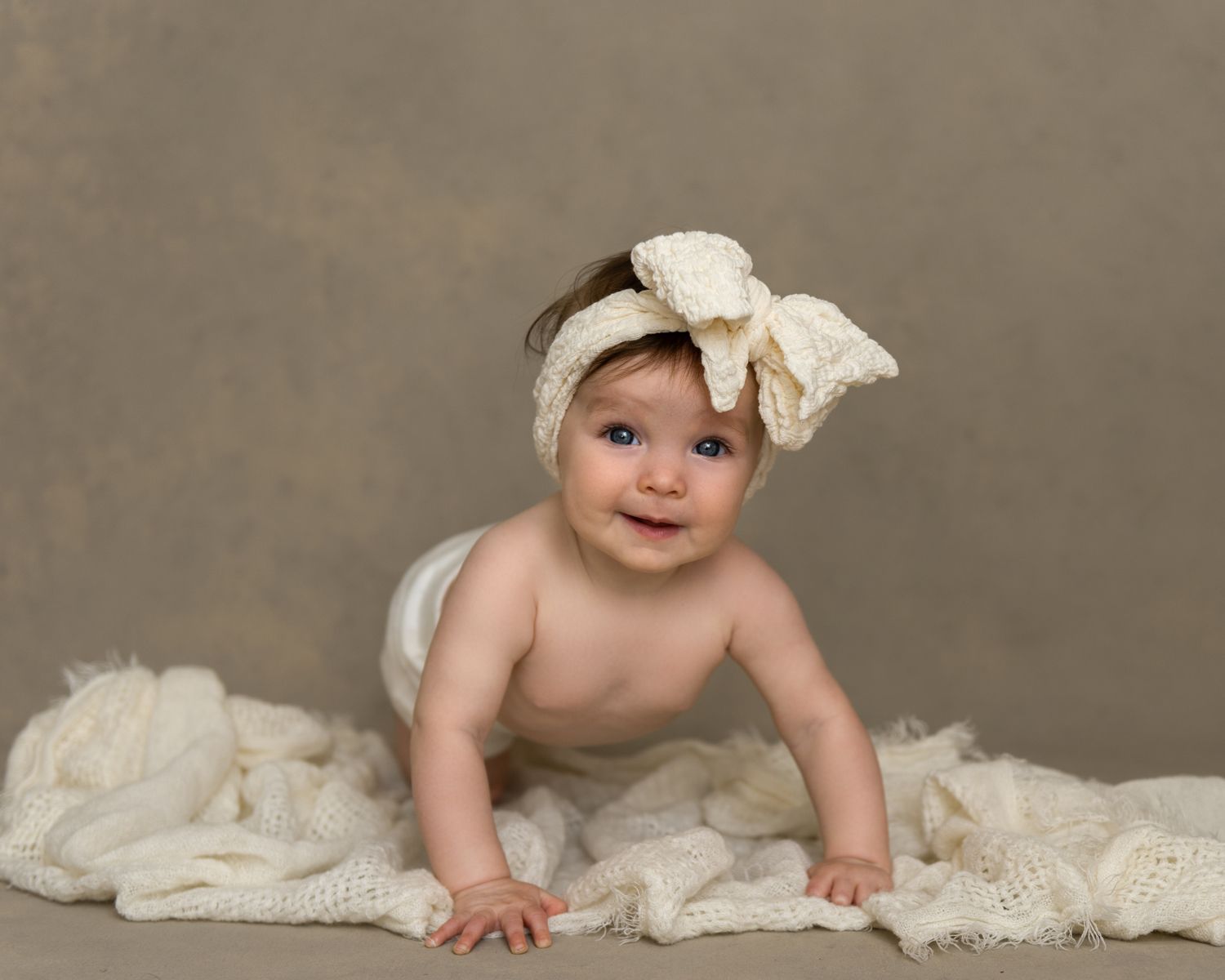 Baby crawling sequence on cream backdrop with lace accessories.