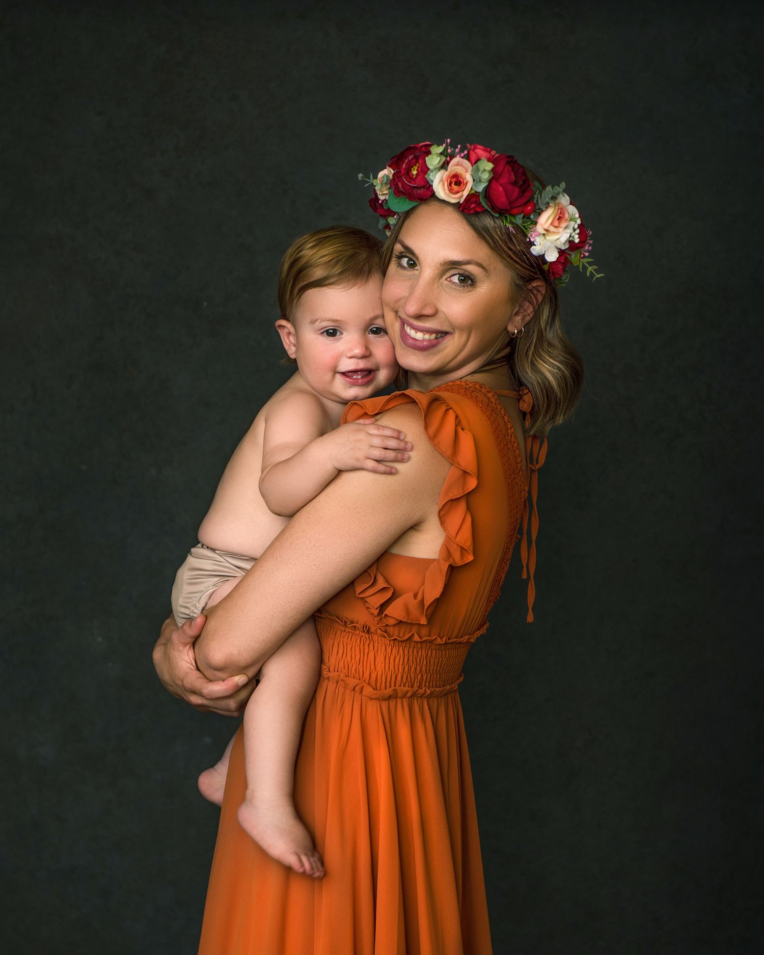 Studio portraits featuring a bright orange dress and floral crown against a dark backdrop.
