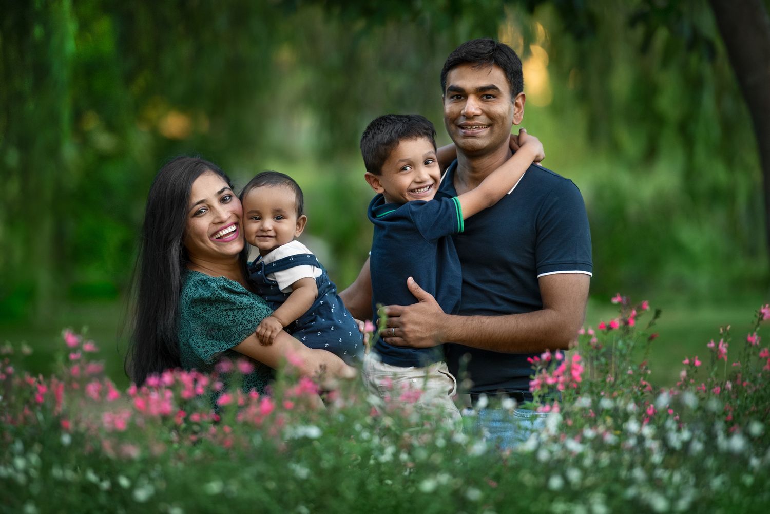 Family portrait session in a blooming garden with pink wildflowers.