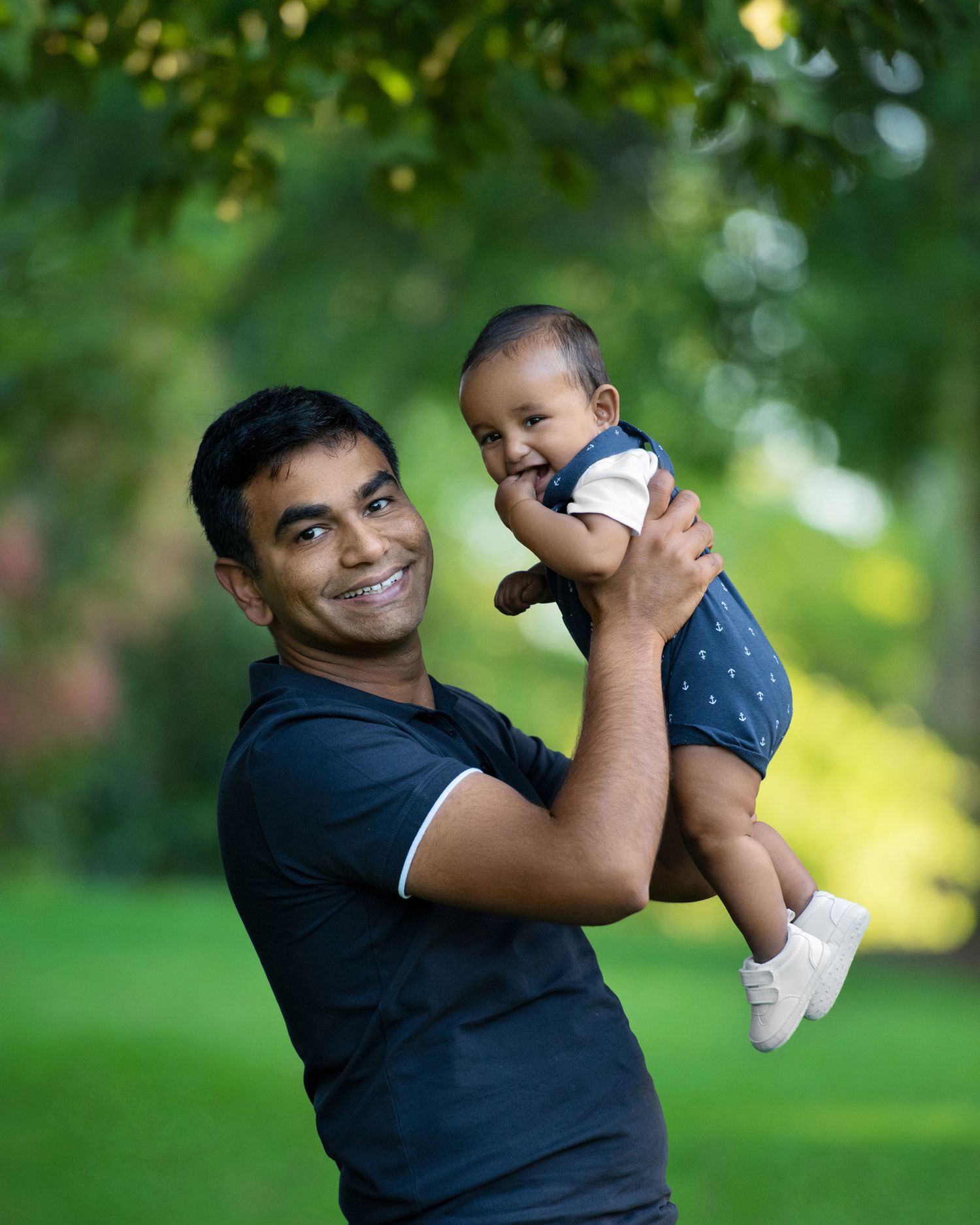 A joyful moment shared between parent and baby in a sunny garden setting.