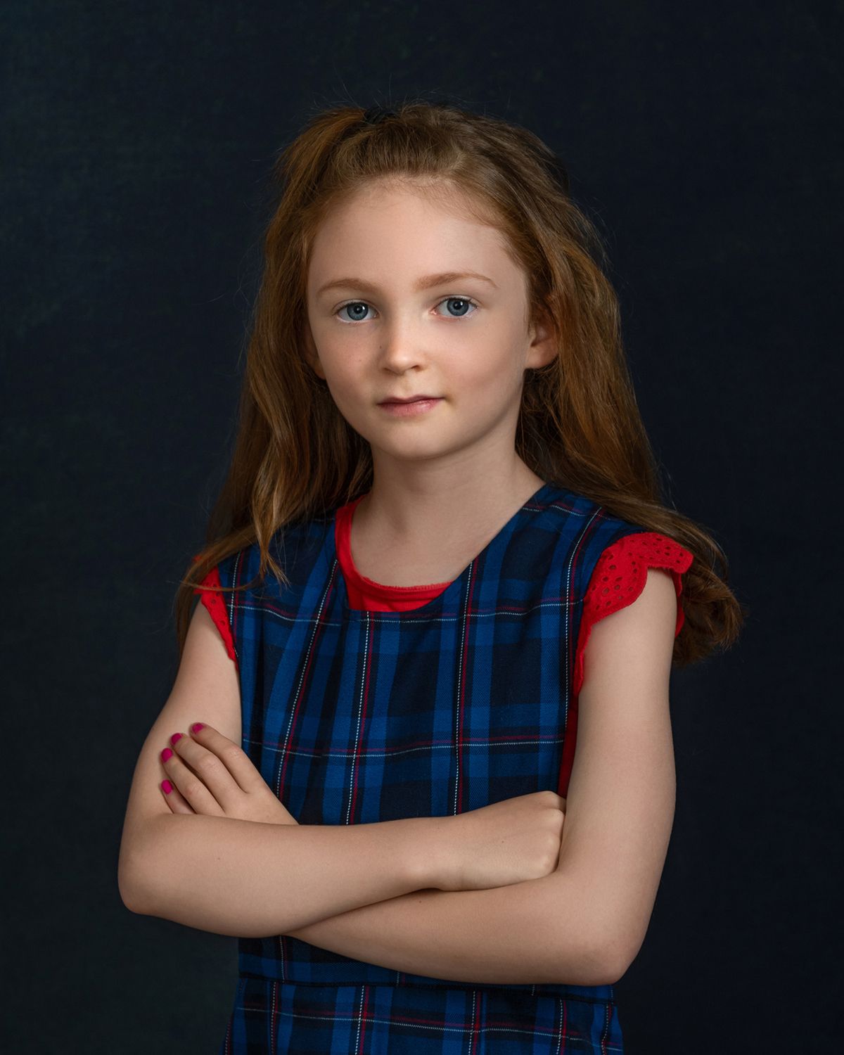 Portrait in blue and red plaid dress against dark studio background.