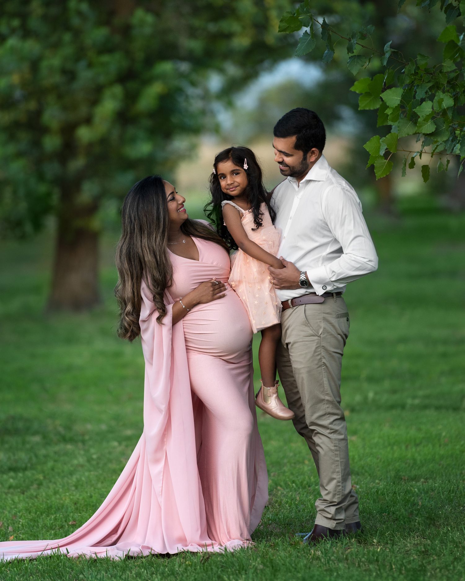 Family maternity photos in pink dress and khaki outdoors at sunset.