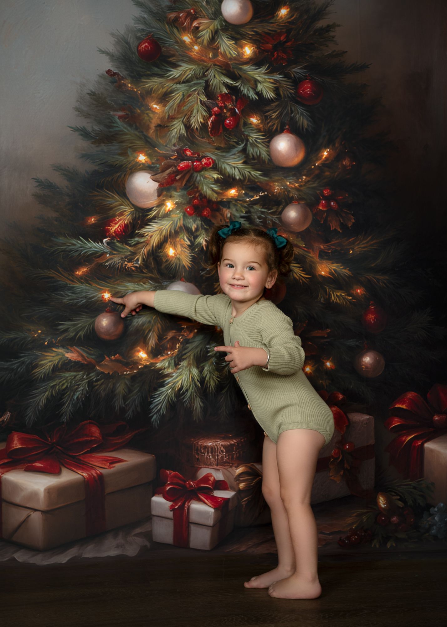 Young child in green outfit plays near decorated Christmas tree with wrapped presents.