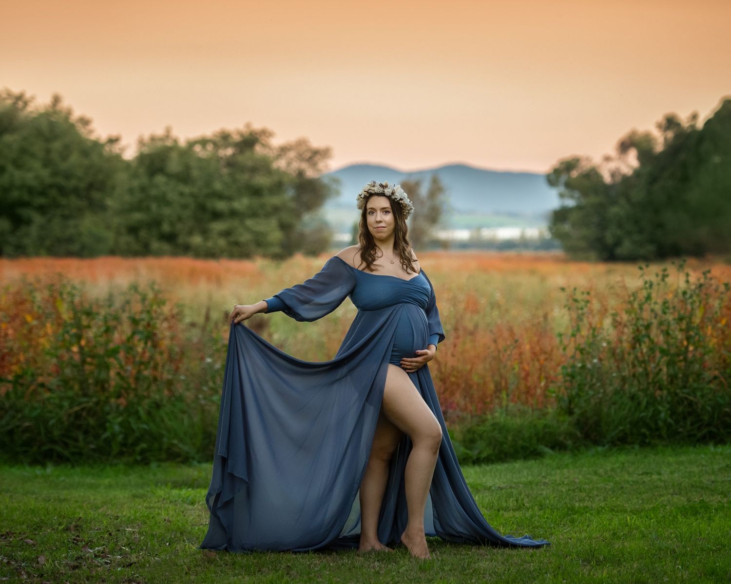 Sunset maternity session in field with flowing navy blue dress.
