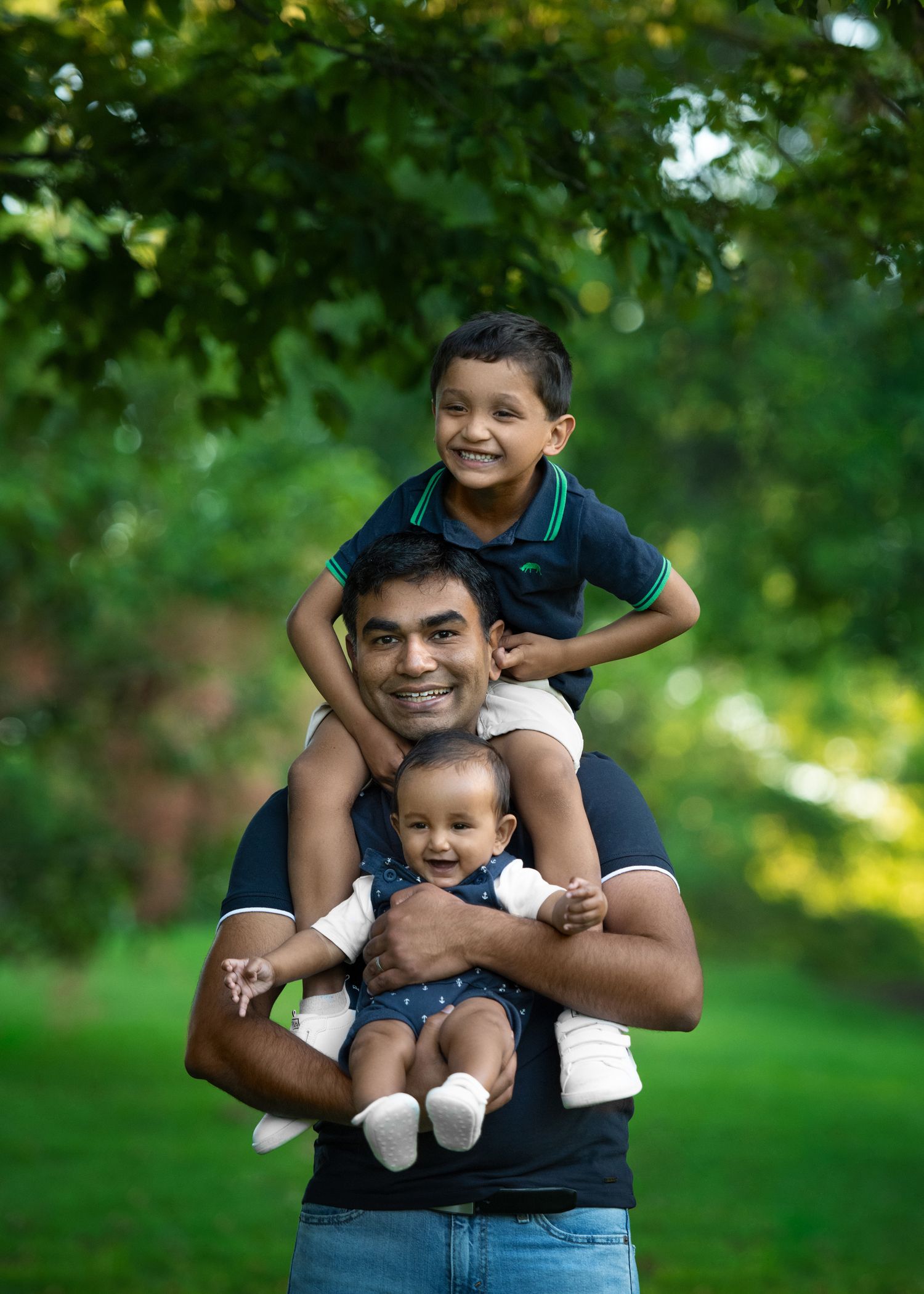 A joyful outdoor family portrait session in a lush green park setting on a sunny day.