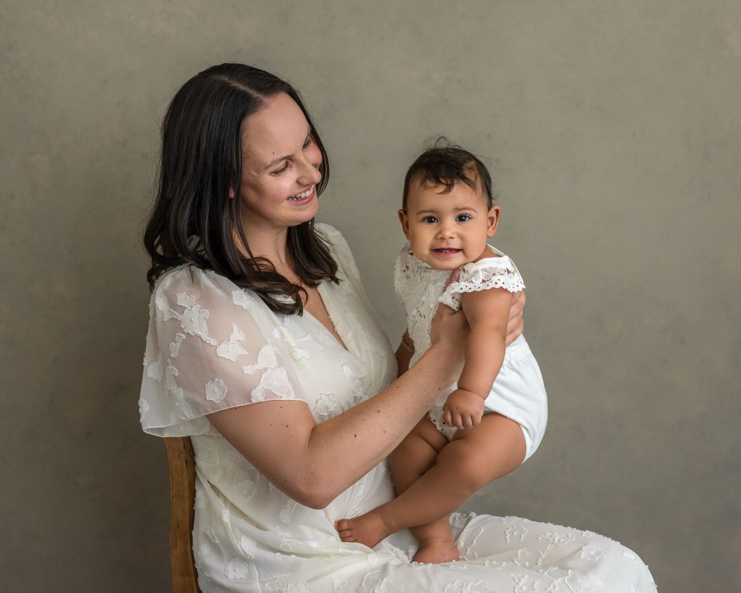 Intimate mother and child portrait session against neutral grey background.