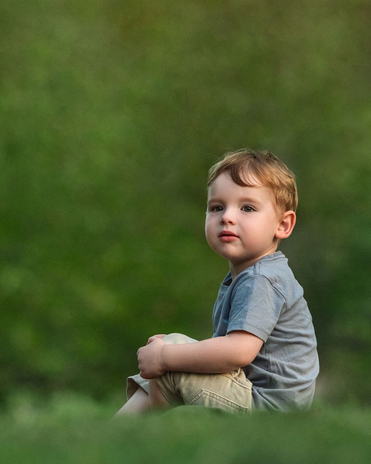 A casual outdoor portrait session against a blurred natural green background.