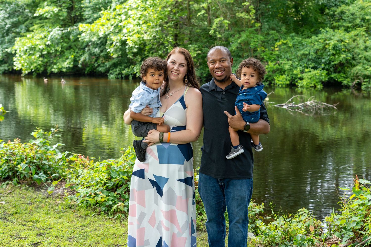 Group photo session by a scenic pond with lush greenery in the background.