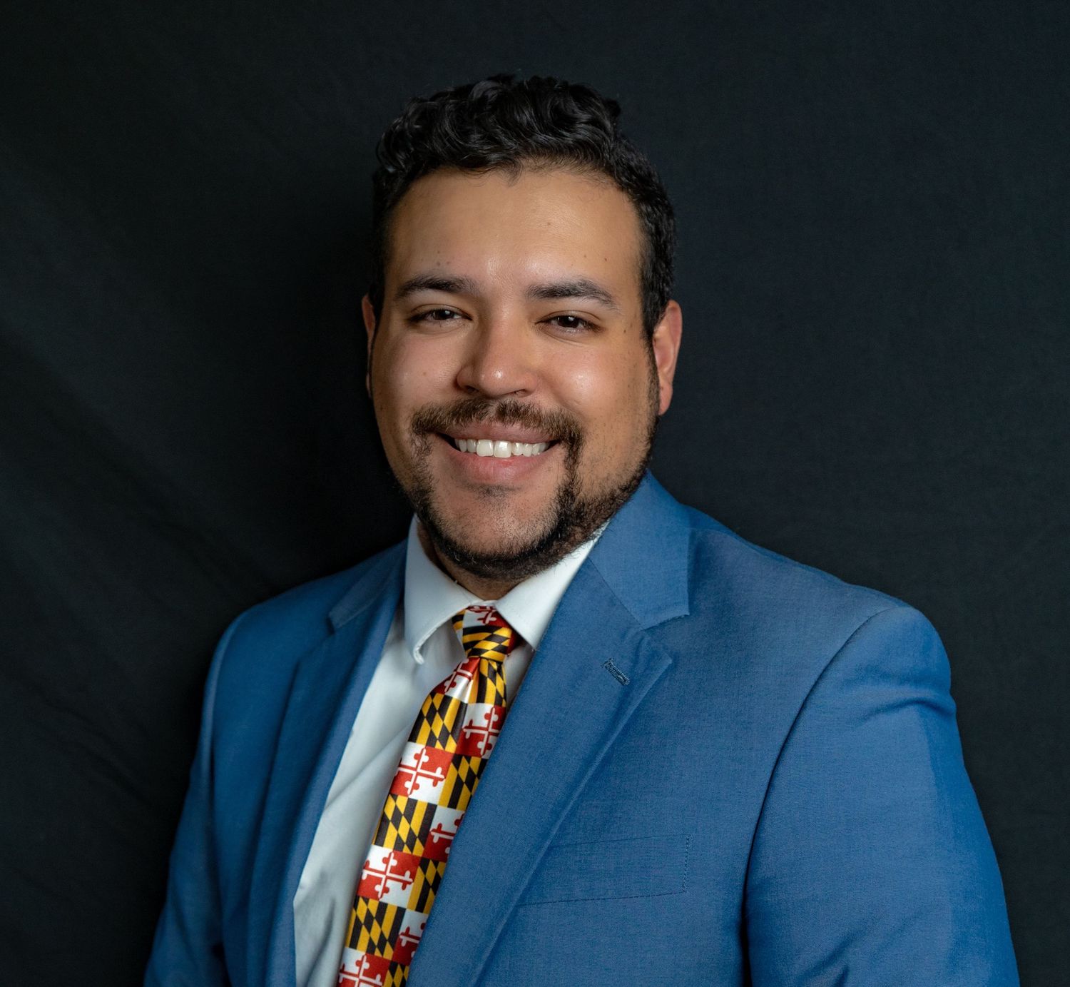 Professional portrait series against dark backdrop featuring person in blue suit and colorful patterned tie.