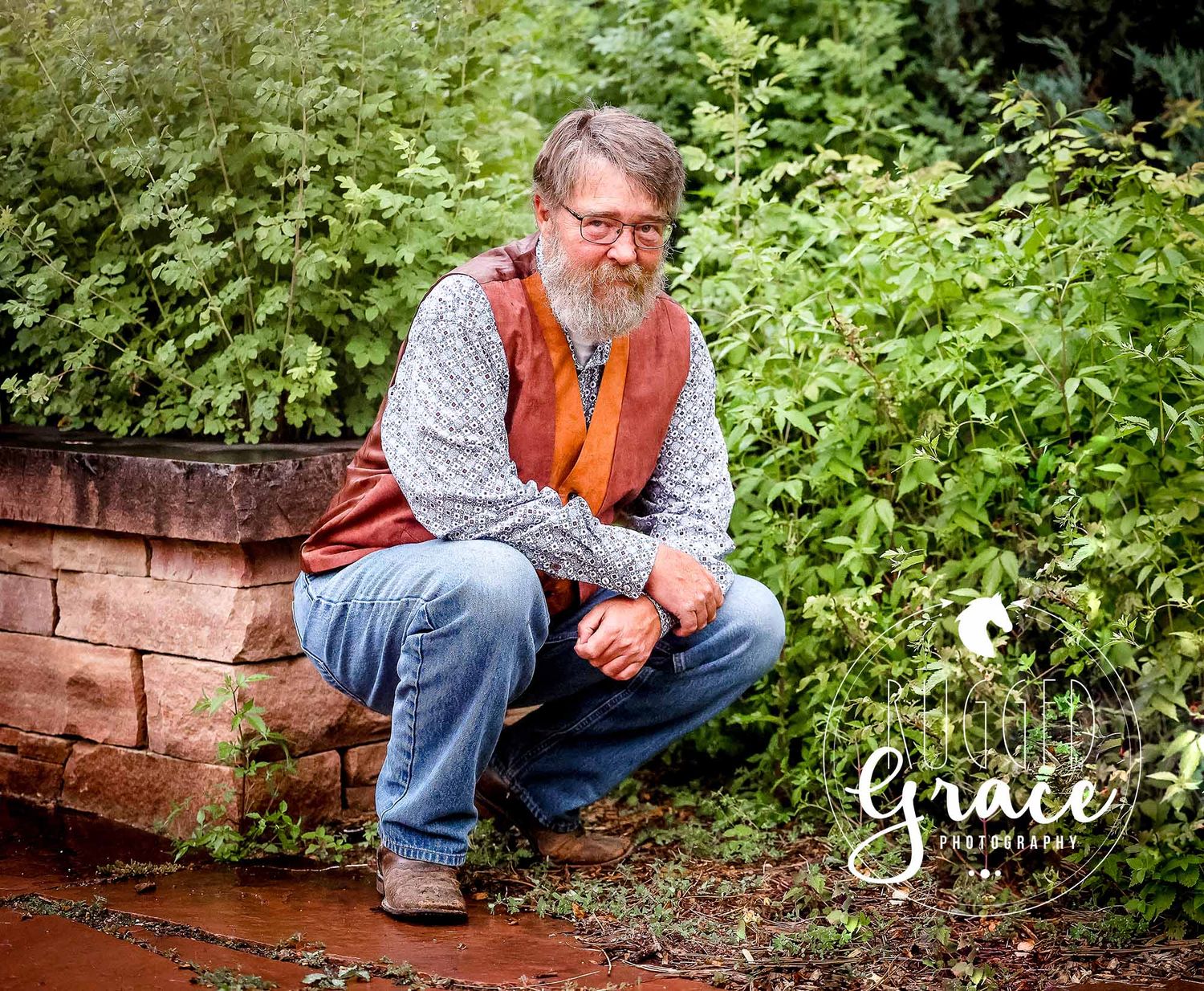 Person sitting on brick steps surrounded by greenery in outdoor portrait session.