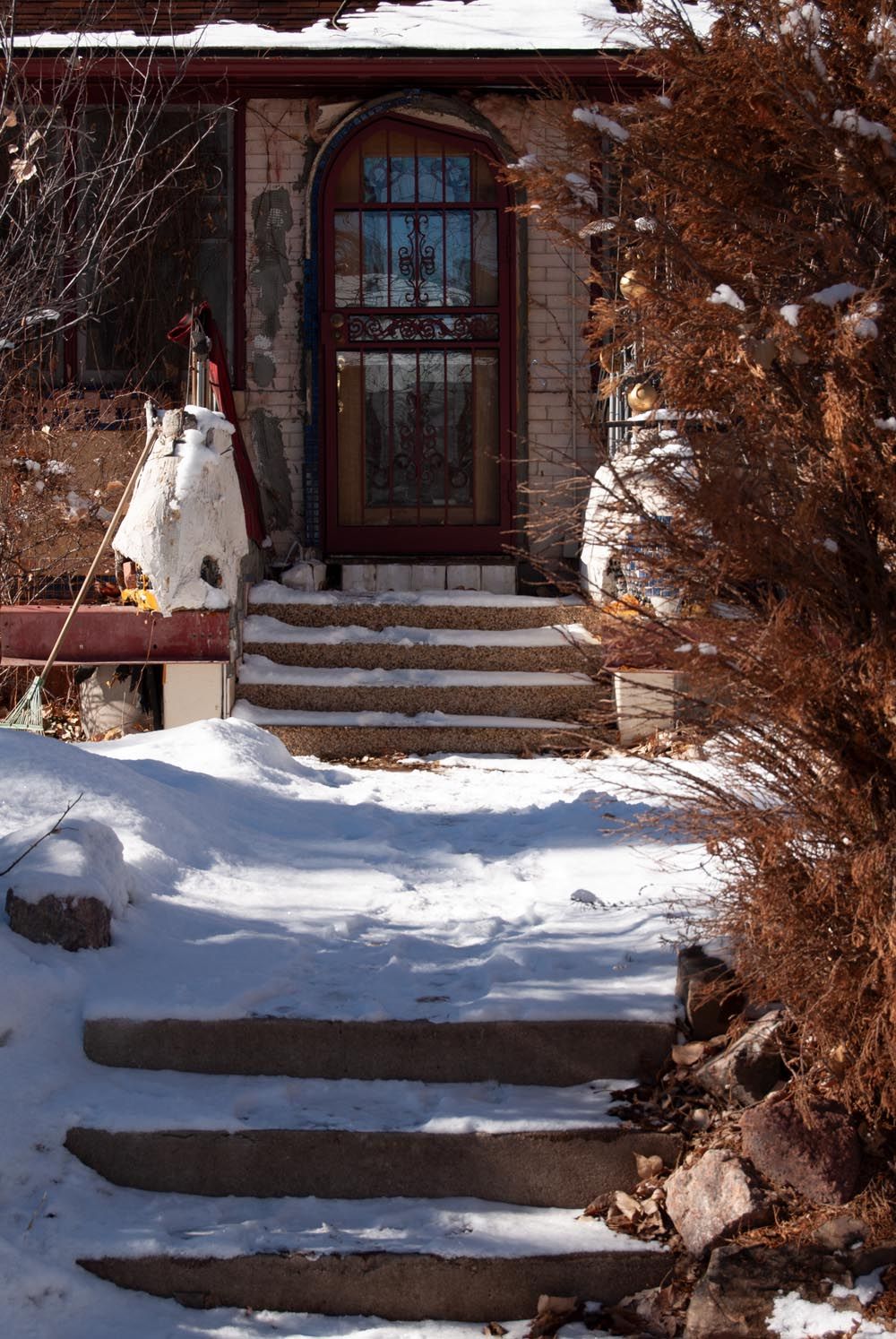 Snow-covered stone steps lead to a historic building with arched windows in winter.