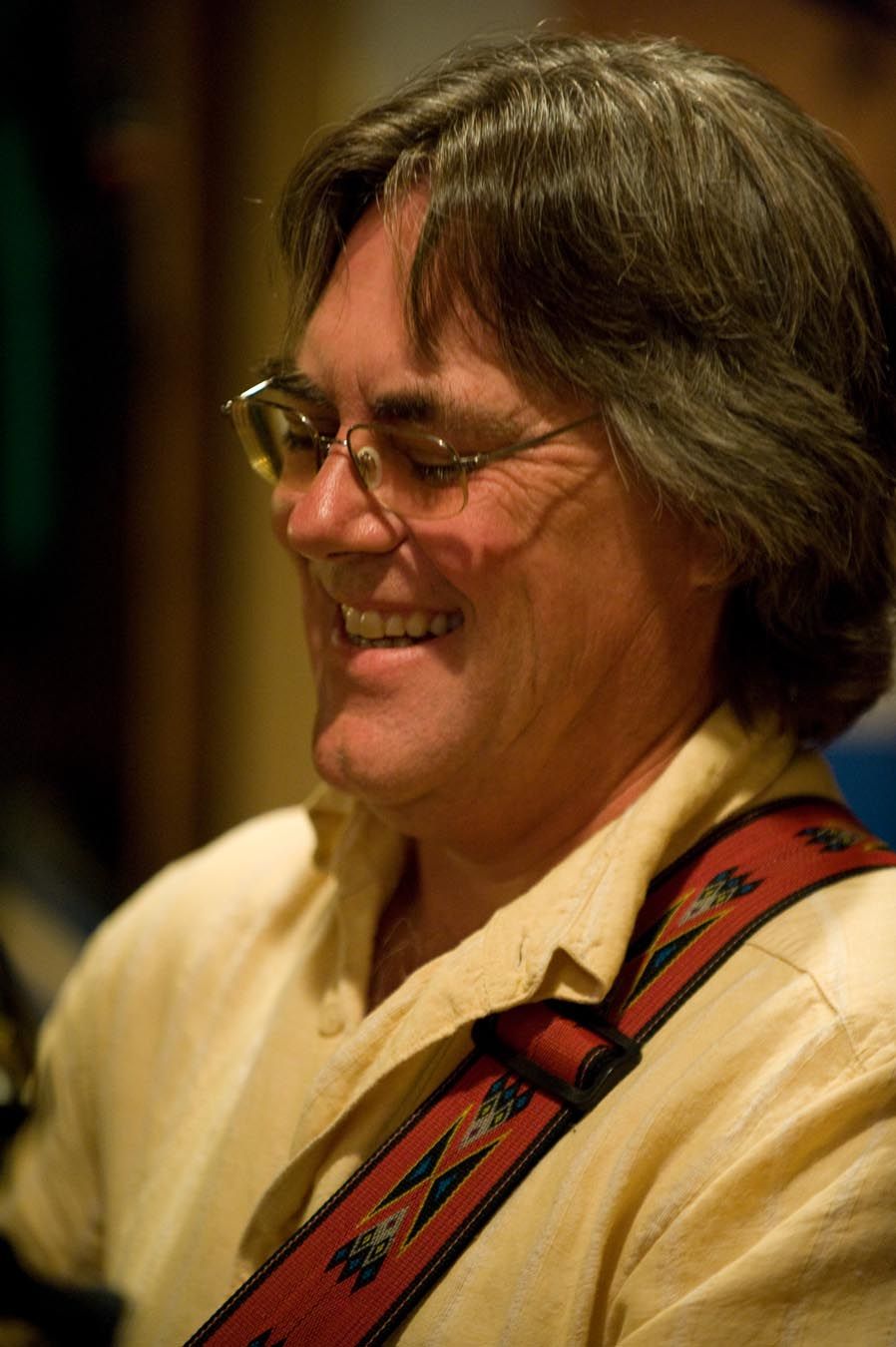 Person wearing glasses and cream colored clothing smiles warmly in a series of candid expressions.