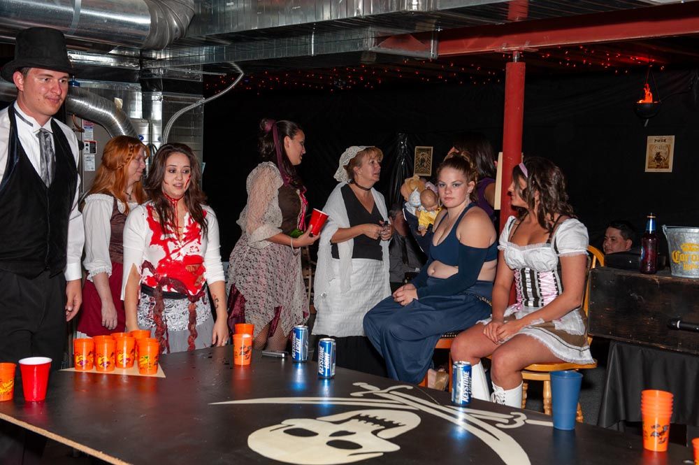 Panoramic view of a dimly lit nightclub bar with patrons seated and standing around the counter area.