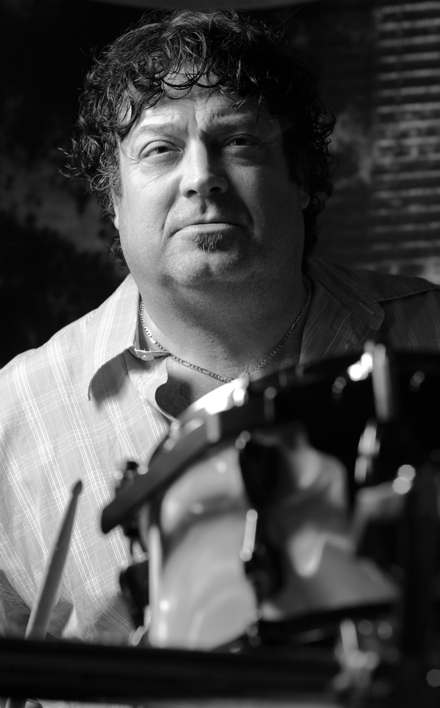 Black and white portrait of a musician with curly hair holding an instrument.