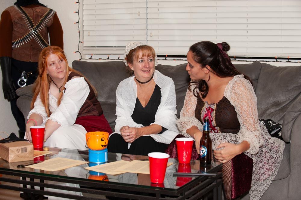 A group of people sitting at a long table having a social gathering with red cups and casual conversation.