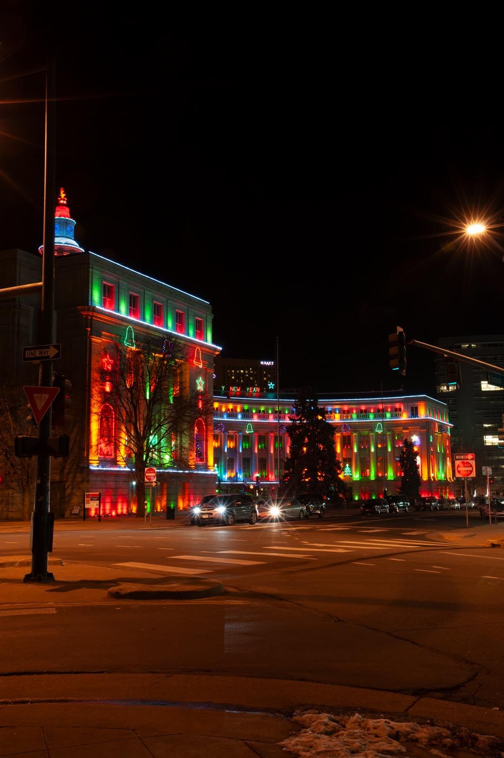 Historic downtown buildings illuminated with colorful Christmas lights against a dark night sky.