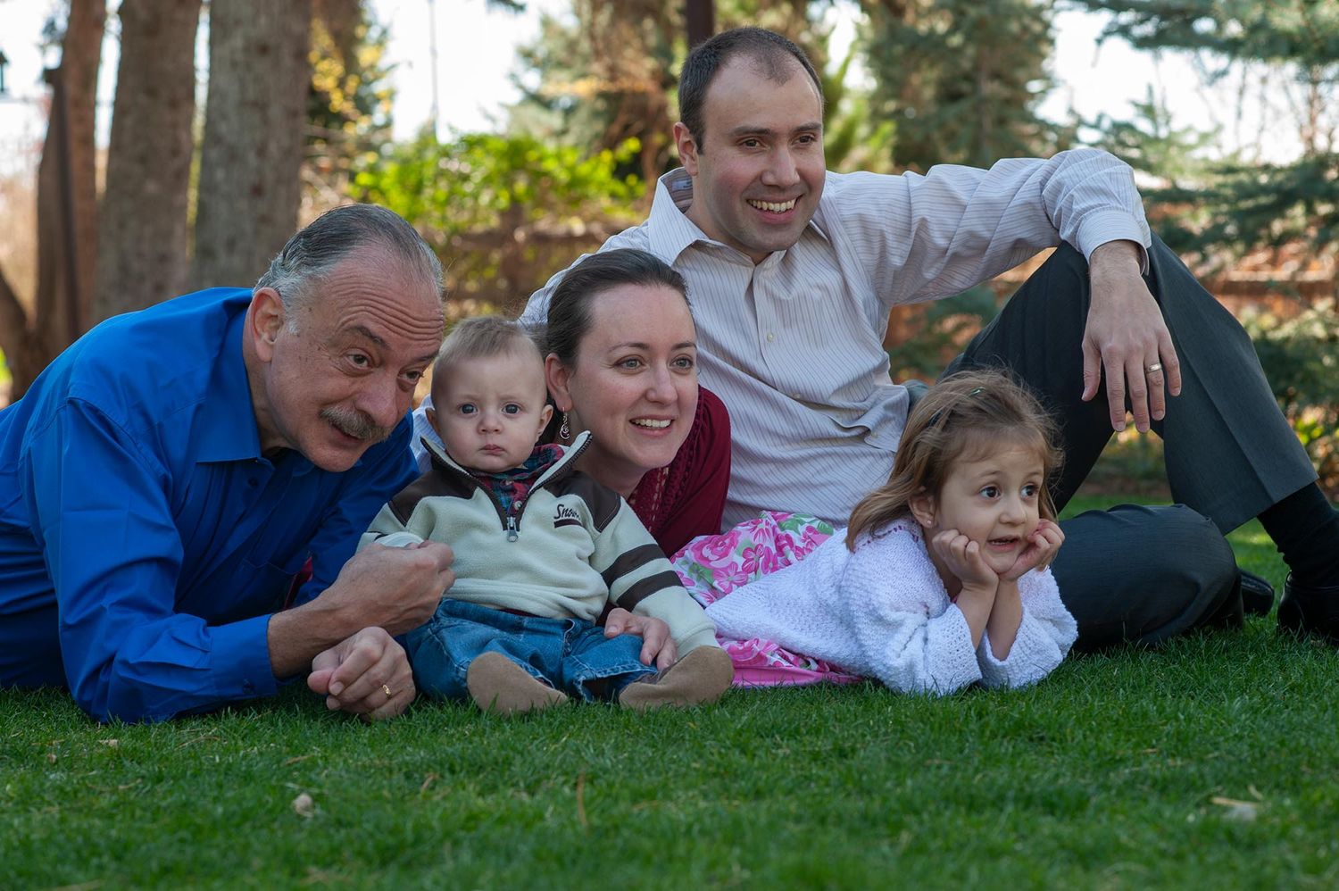 Family lying together on grass during outdoor photo session.