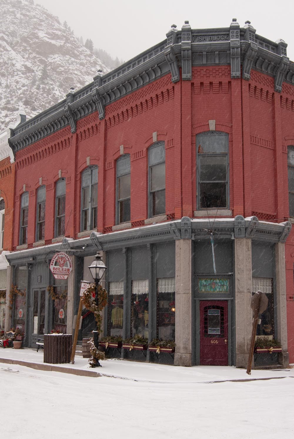 Historic red brick corner building with ornate architecture covered in fresh snow.