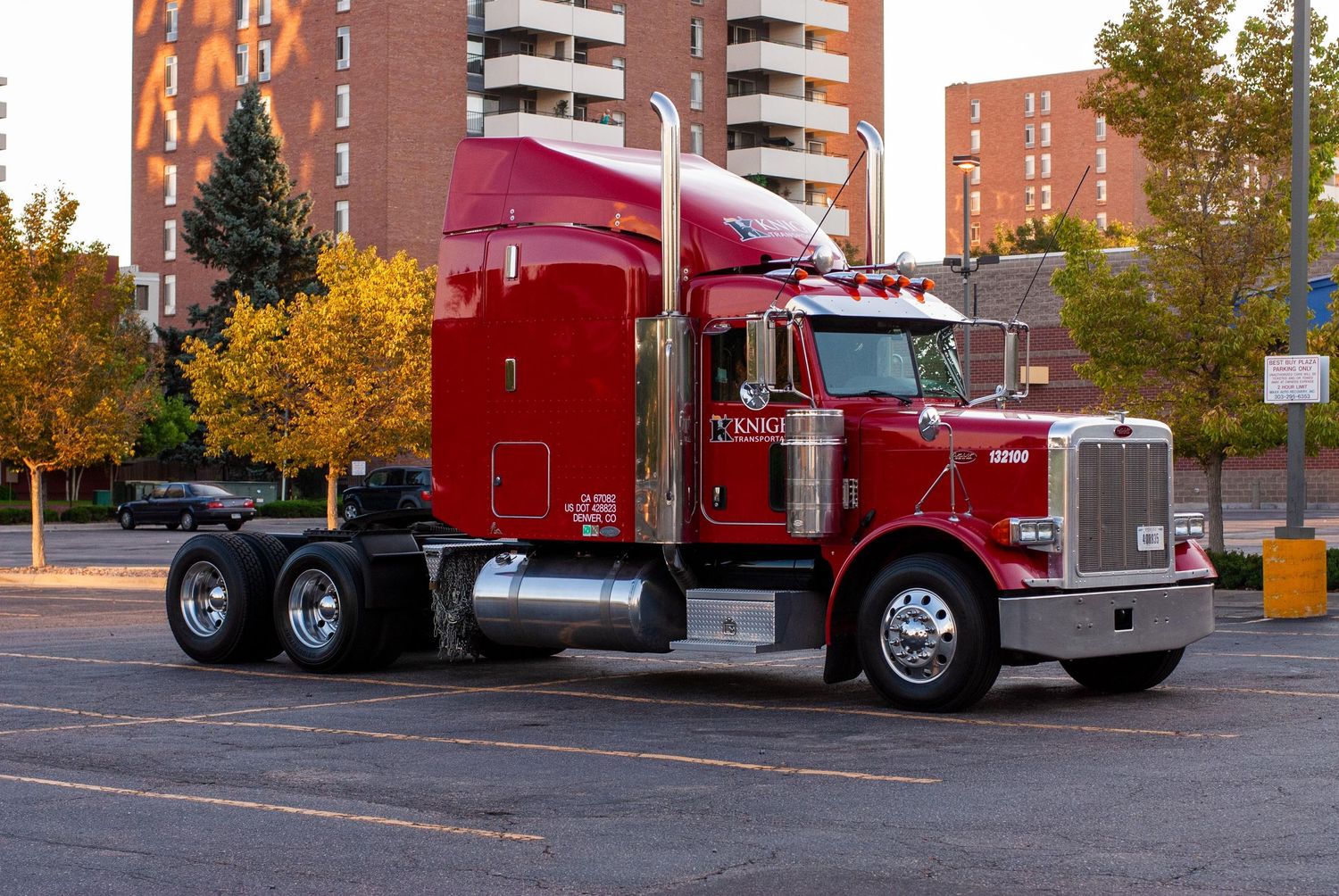 Red semi truck with chrome details parked on street near residential buildings.