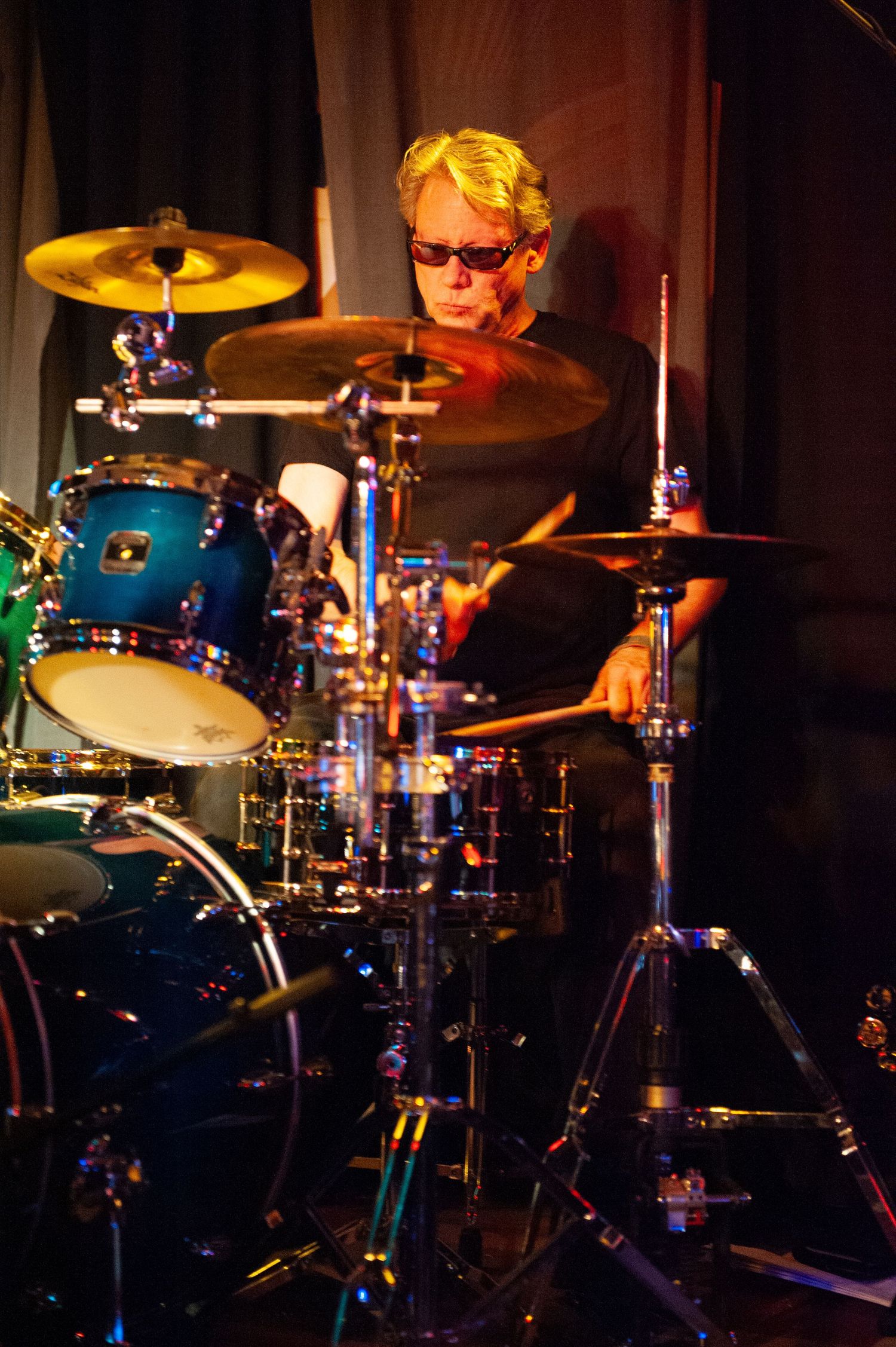 Drum kit illuminated by colorful stage lights during a performance.