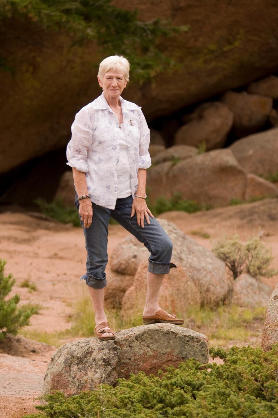 Person in white shirt and dark pants explores rocky terrain outdoors.