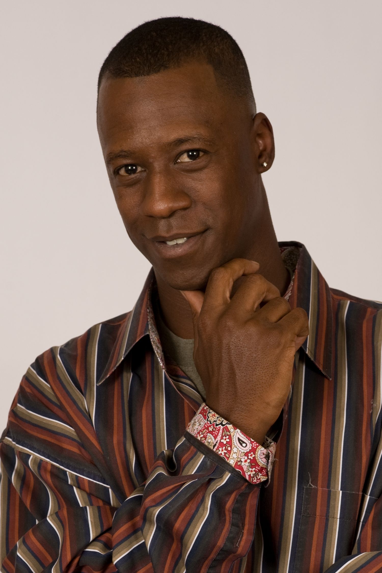 Studio portrait in striped shirt against light gray background.