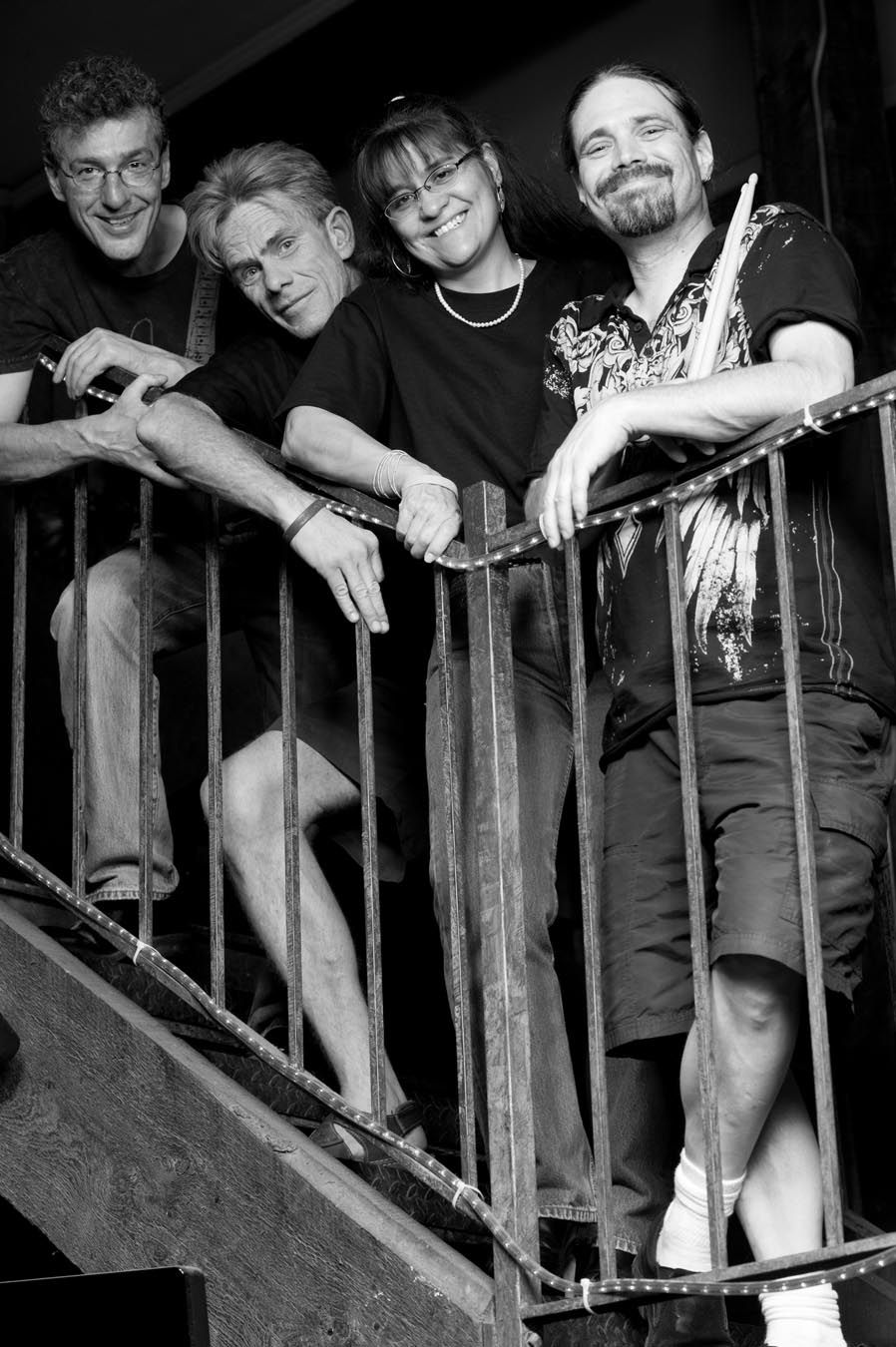 Group of people leaning against wooden railings in black and white photography.