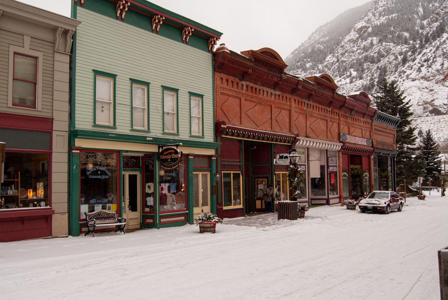 Snow-covered historic storefronts line a quiet small town main street in winter.