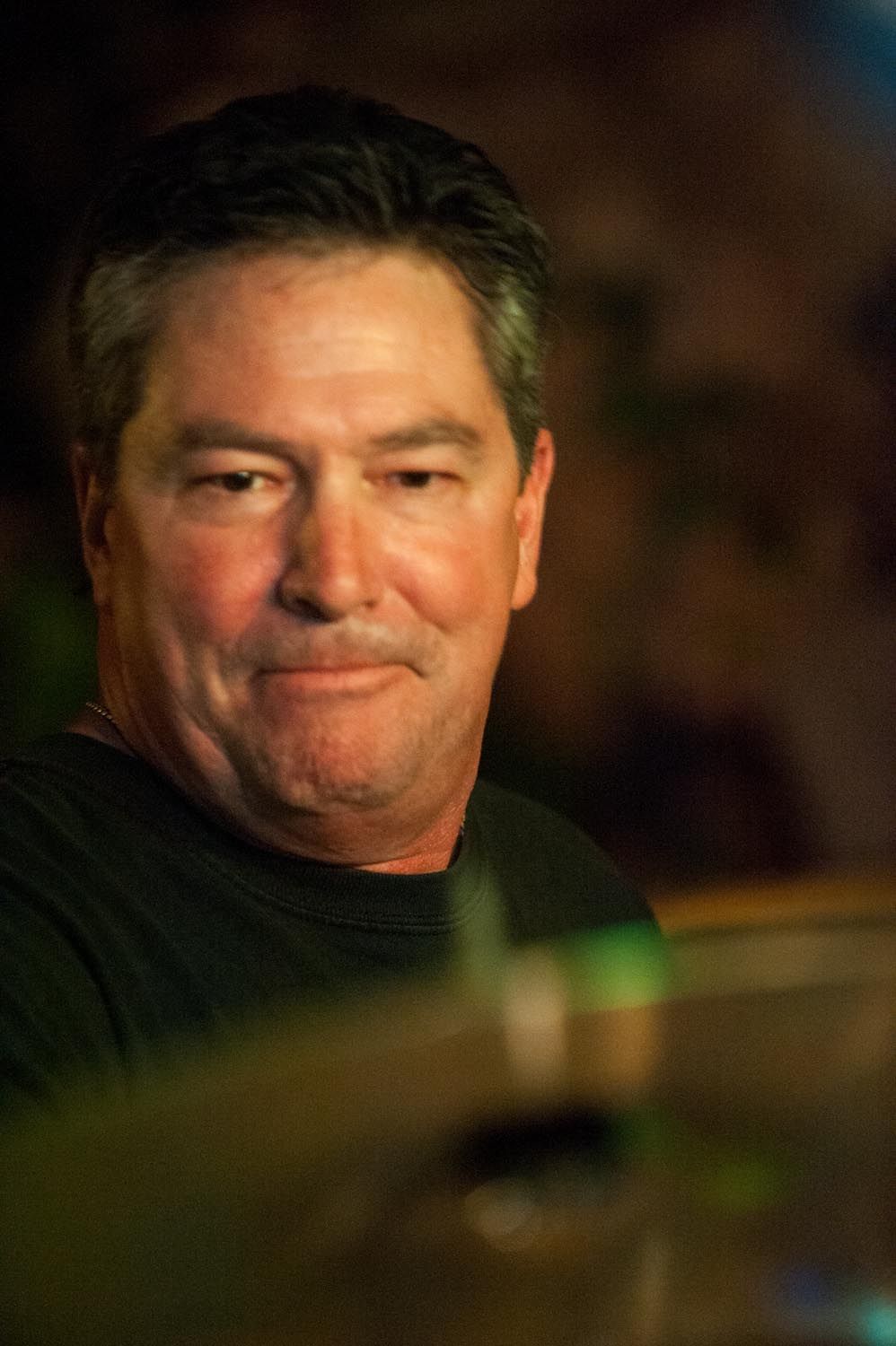 Portrait of a person smiling in dramatic lighting at a performance venue.