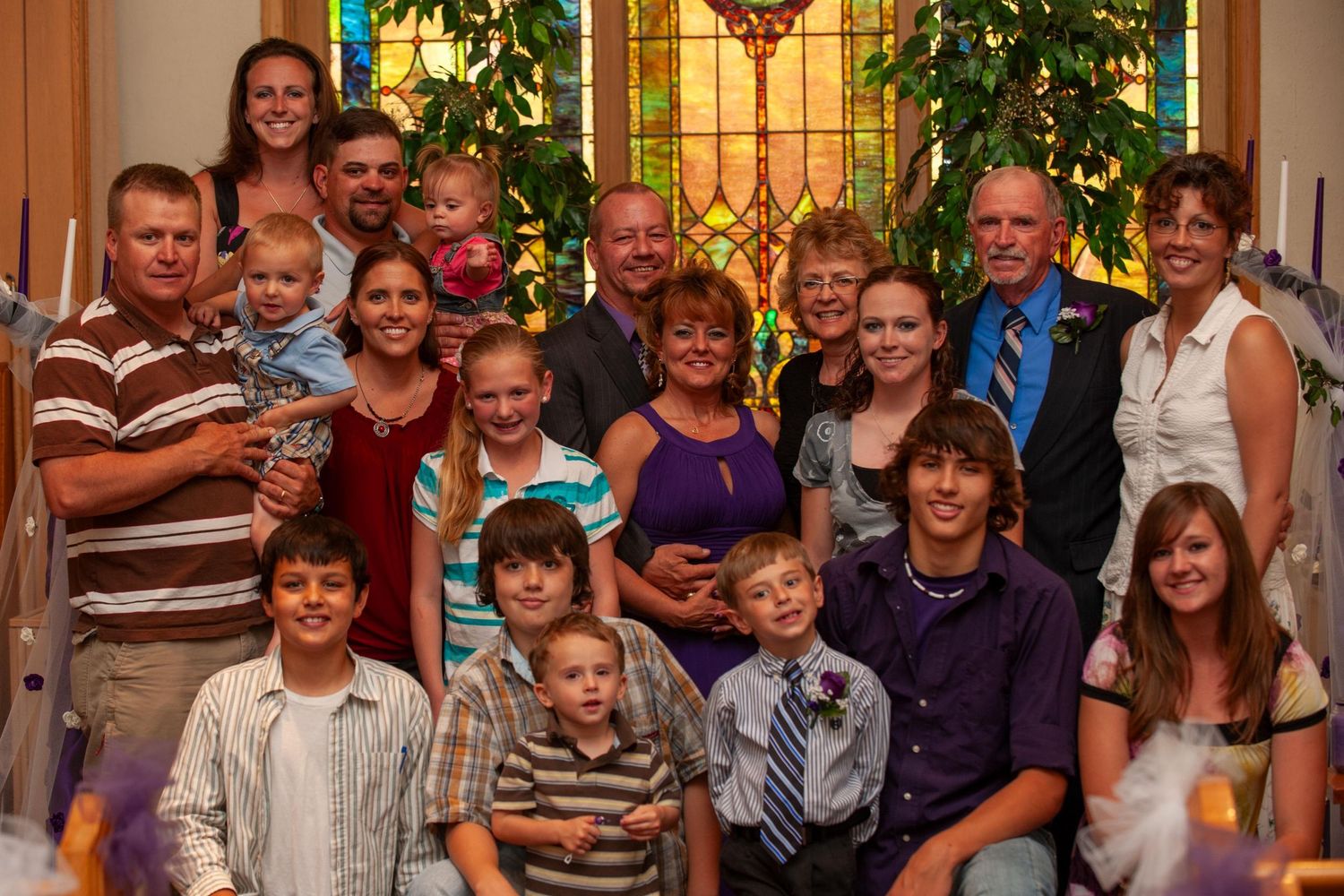 Large group gathering in front of stained glass windows at a church or community event.