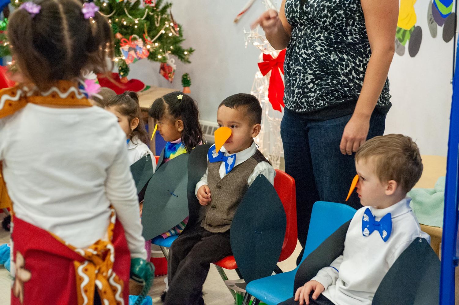 Children and adults gather around a decorated table at a festive party with colorful decorations and balloons.