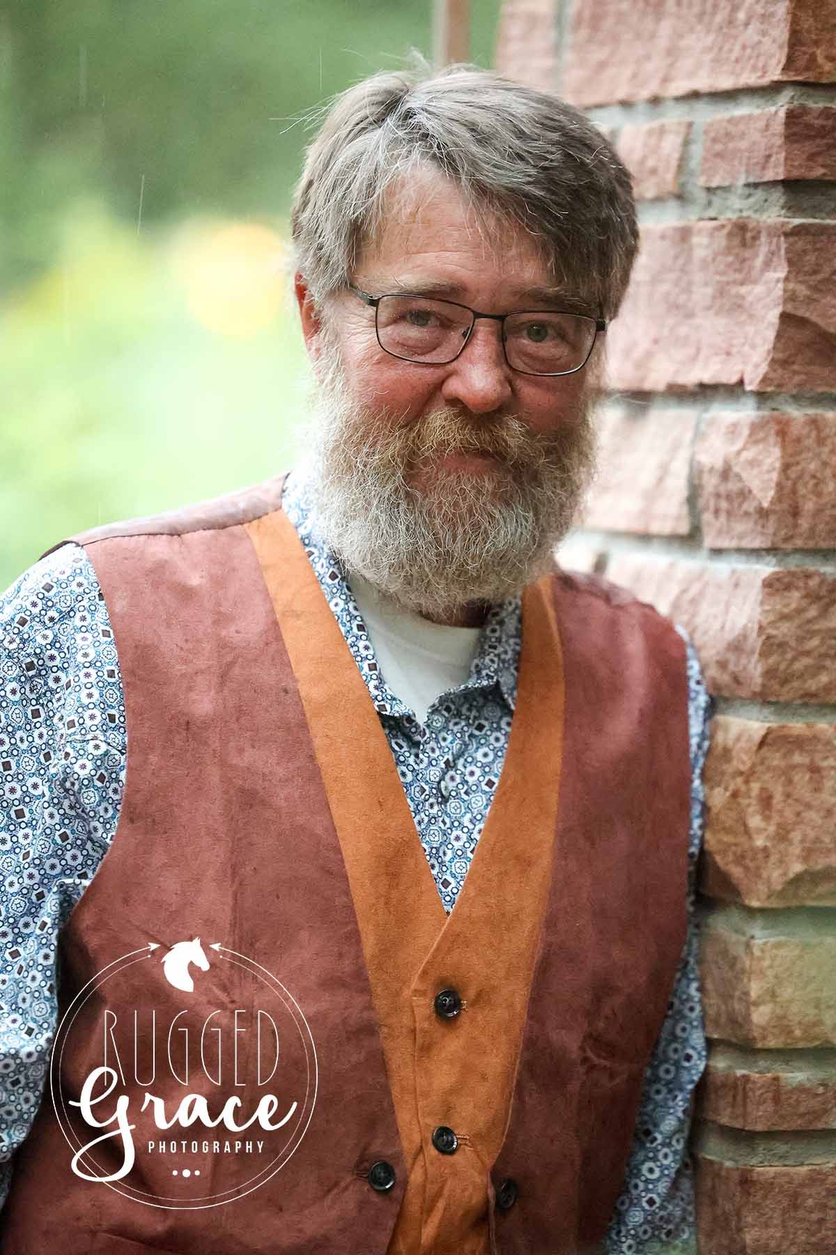 Portrait series showing someone in a leather vest and patterned shirt against a brick wall.