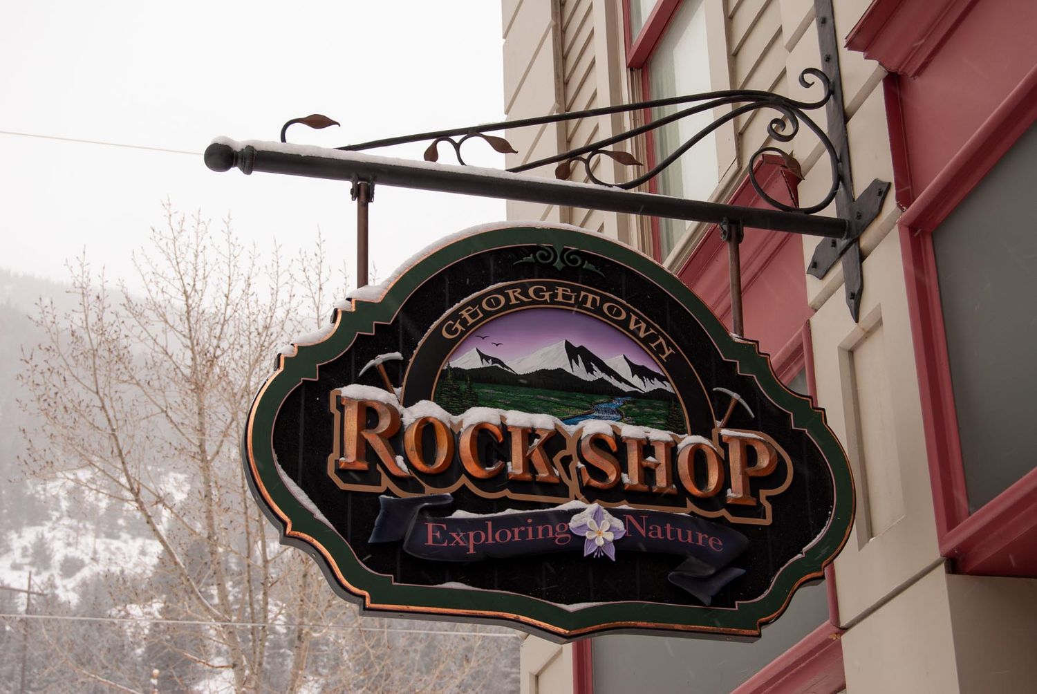 Vintage-style shop signs hang from decorative metal brackets along a storefront.