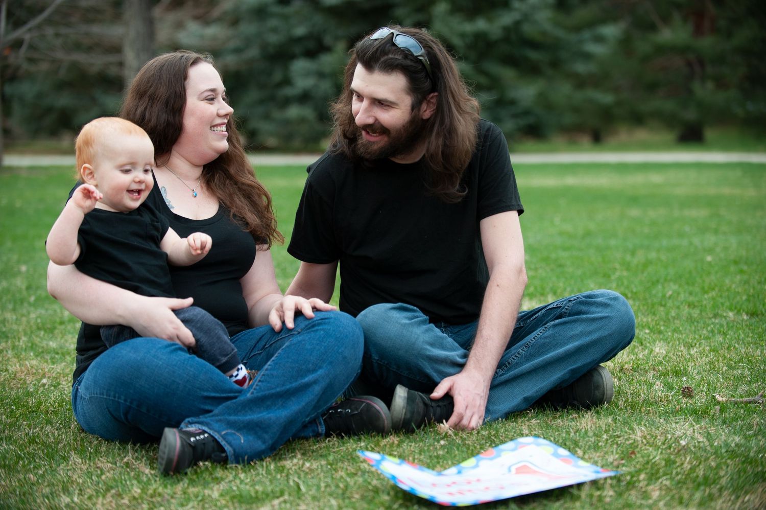 Family sitting together on grass looking at something while relaxing outdoors.