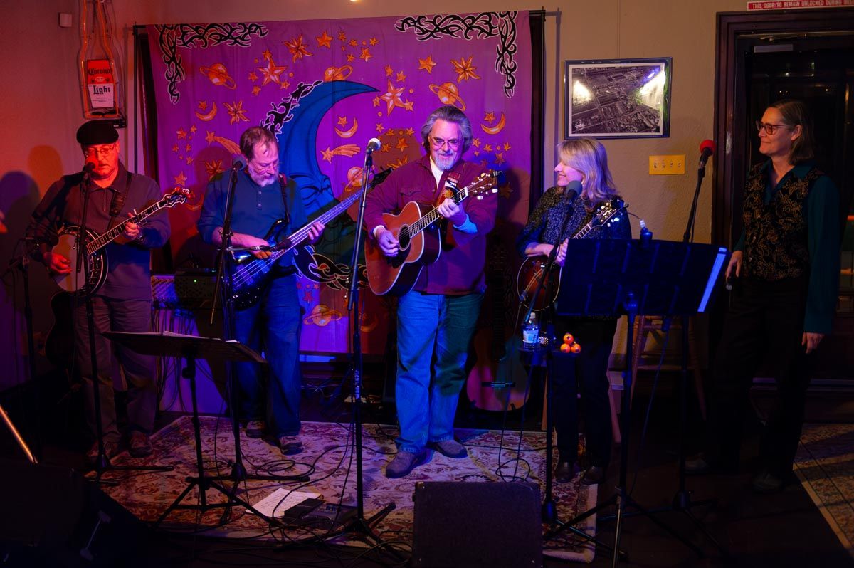 Live music performance at a venue with colorful purple lighting and stage setup.