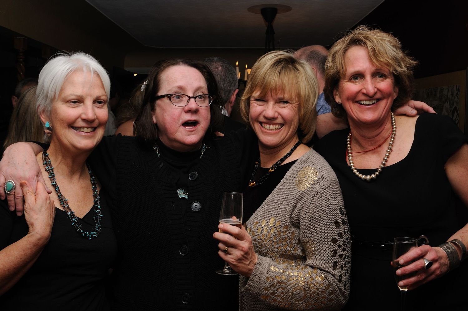 Group gathering at a dimly lit social event with festive attire.