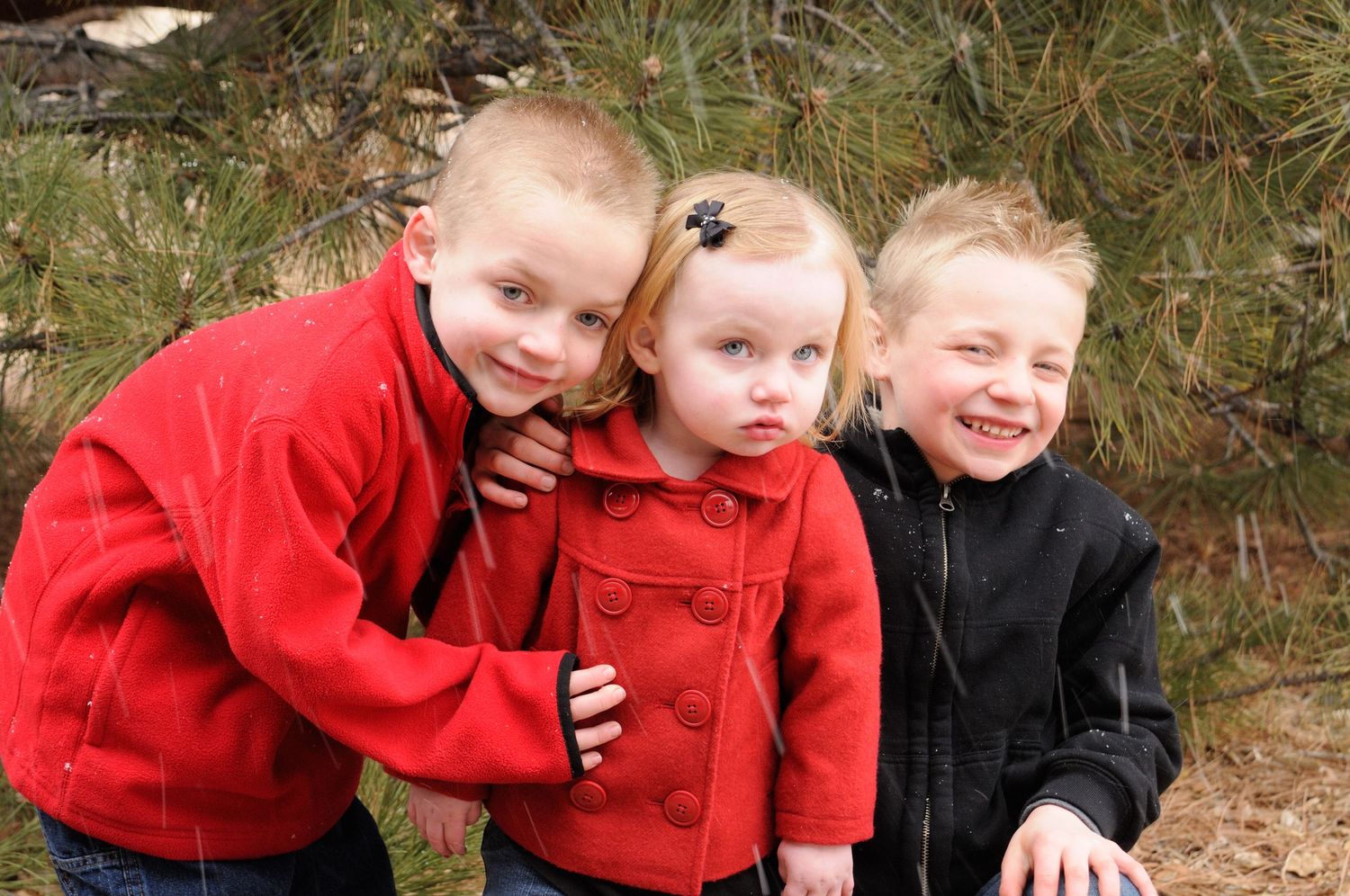 Children in red coats playing and laughing together outdoors.