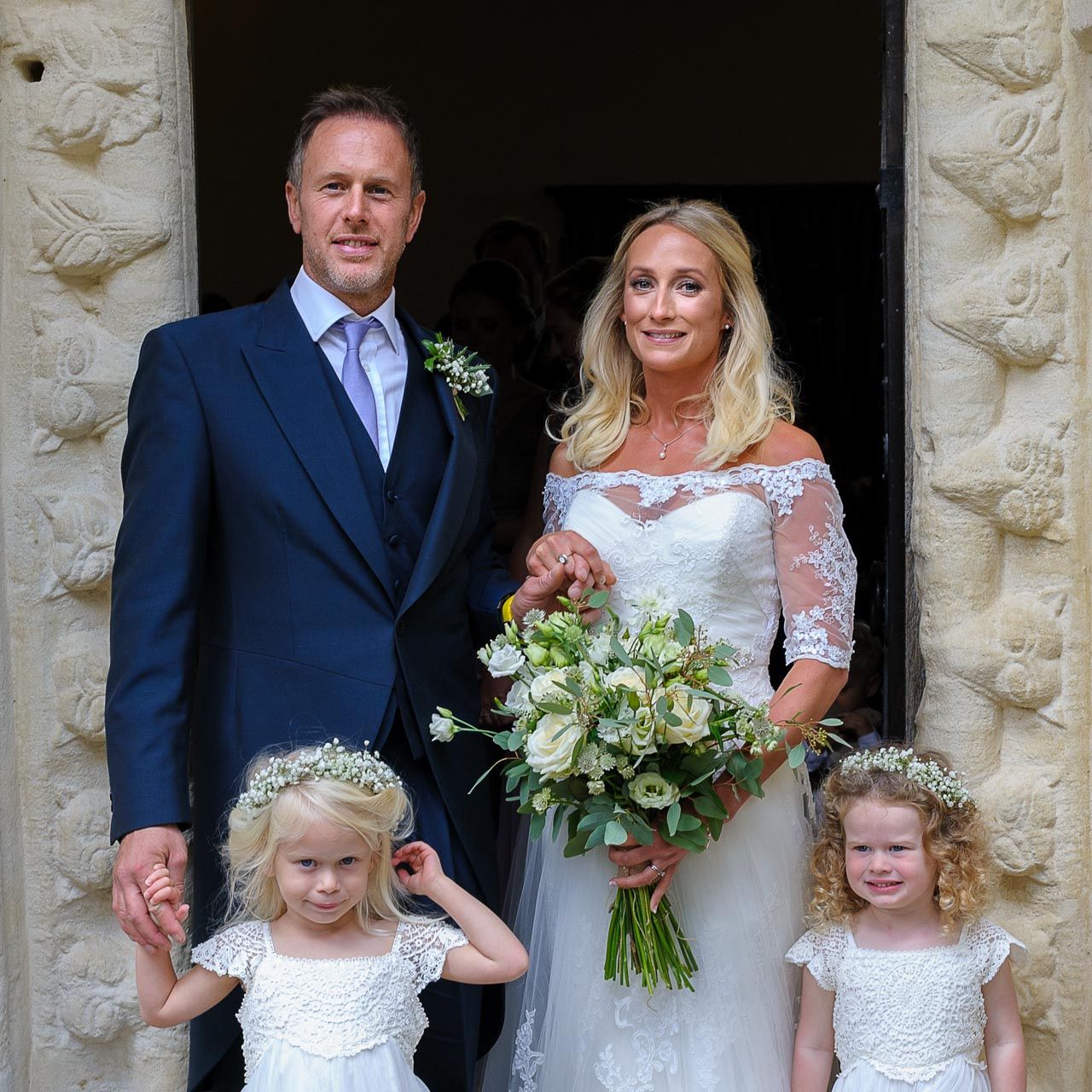 Bride and groom and their children just after the wedding service at St Peters, Windrush in the Cotswolds