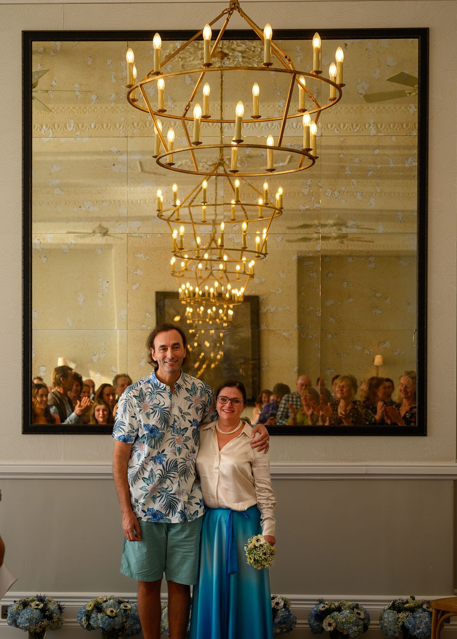 Bride and groom just after the wedding ceremony in a hotel in Fowey, Cornwall. The guests looking on can be seen in the mirror