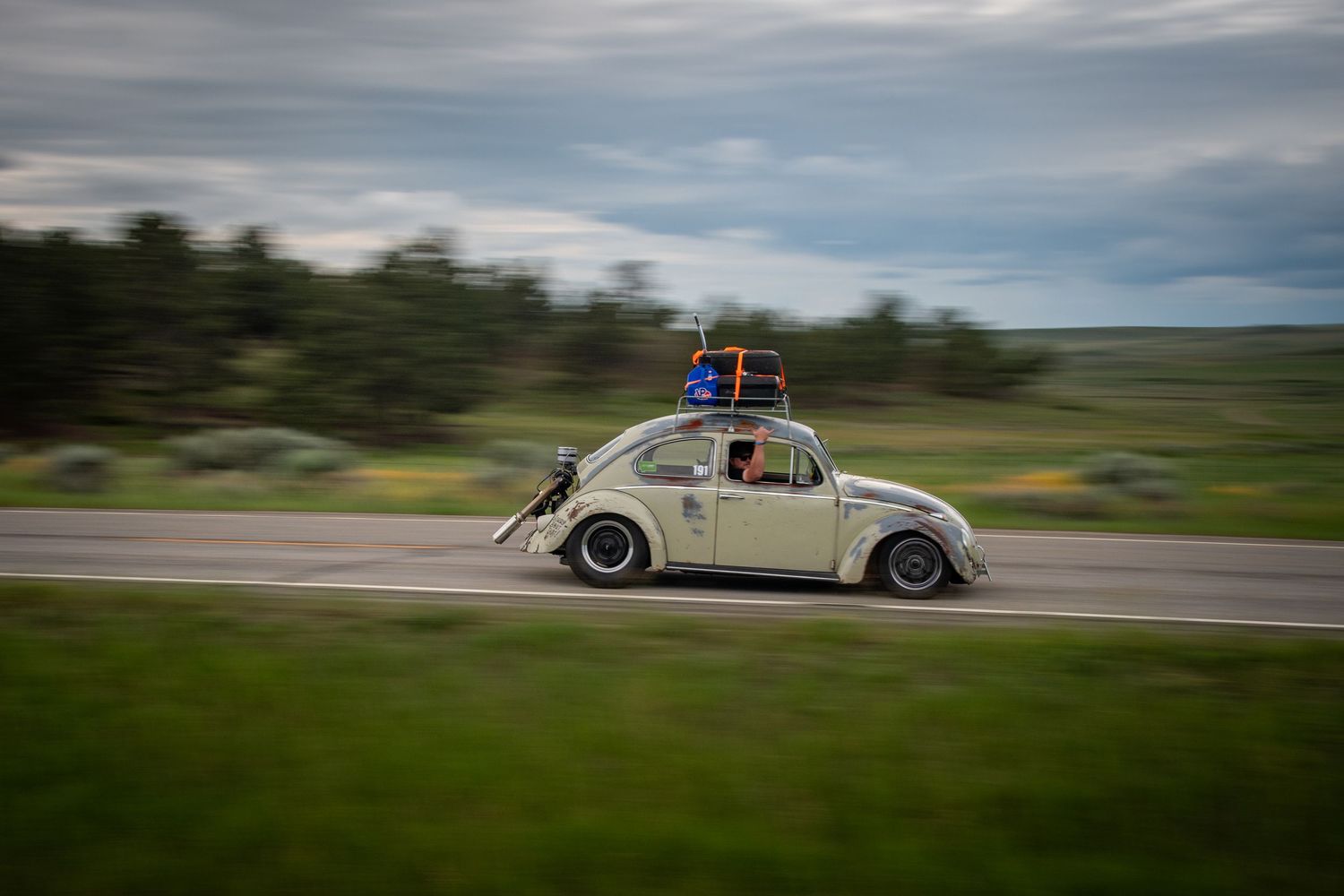 VW bug cruising down the highway in open plains of Montana.