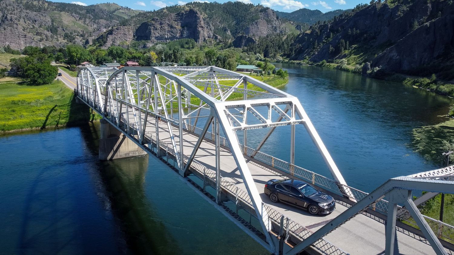 Holden Ute crossing a steel bridge in the Montana rocky mountains with a stunning view of the river and mountains surrounding the car
