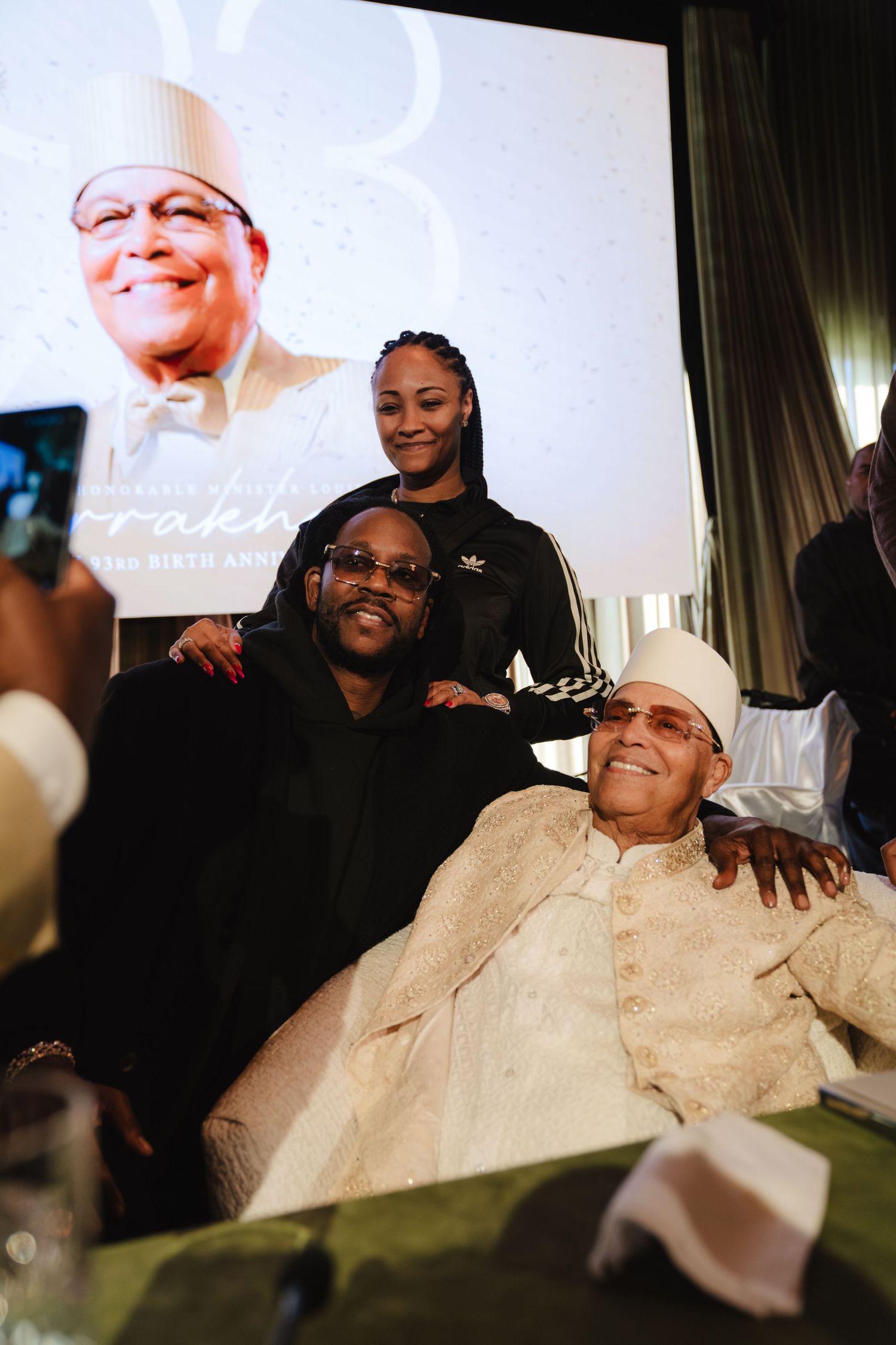 Two men and a woman posing together at a birthday anniversary celebration event.