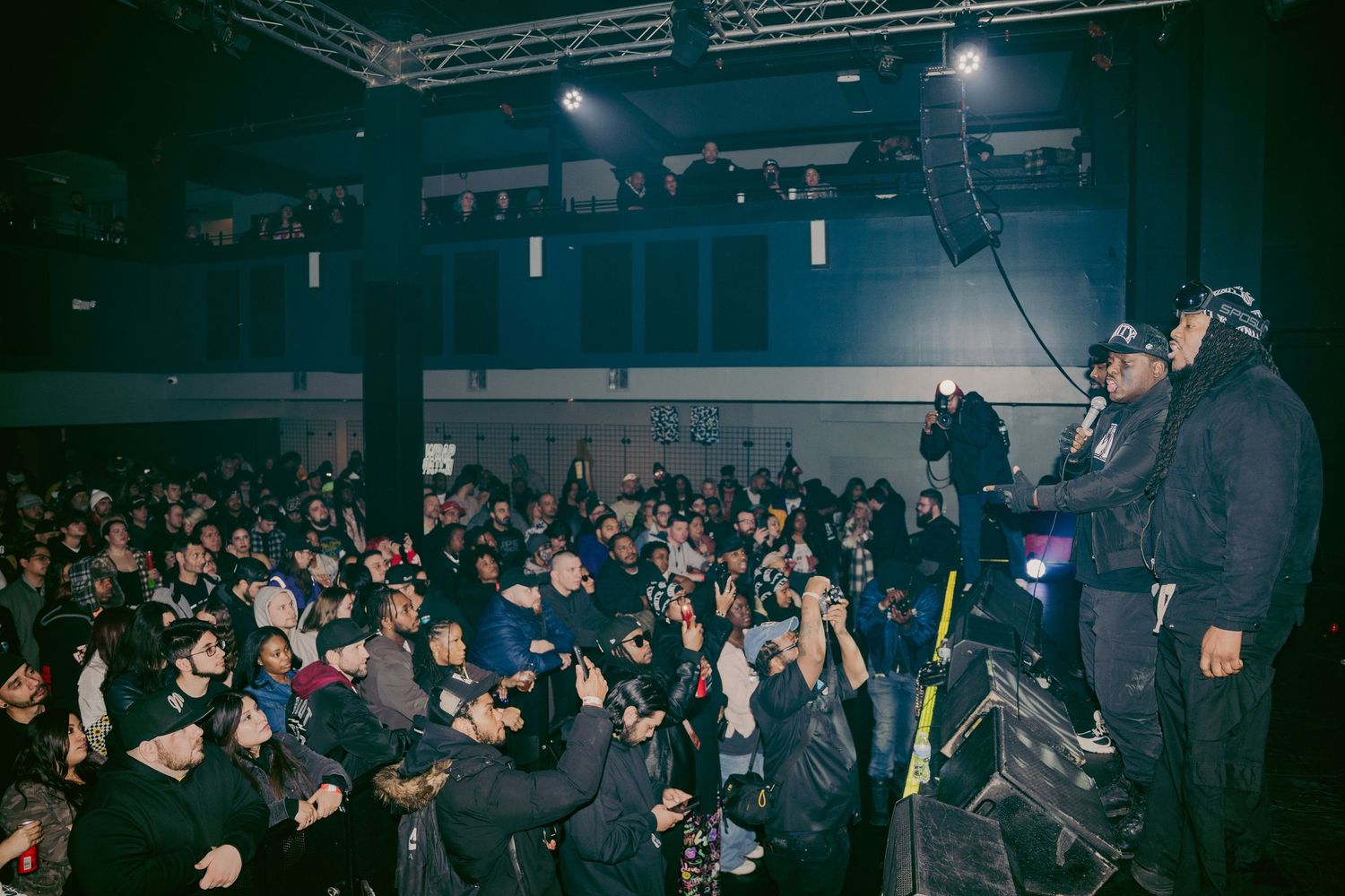 Performer on stage addresses large crowd at indoor Unity concert event.