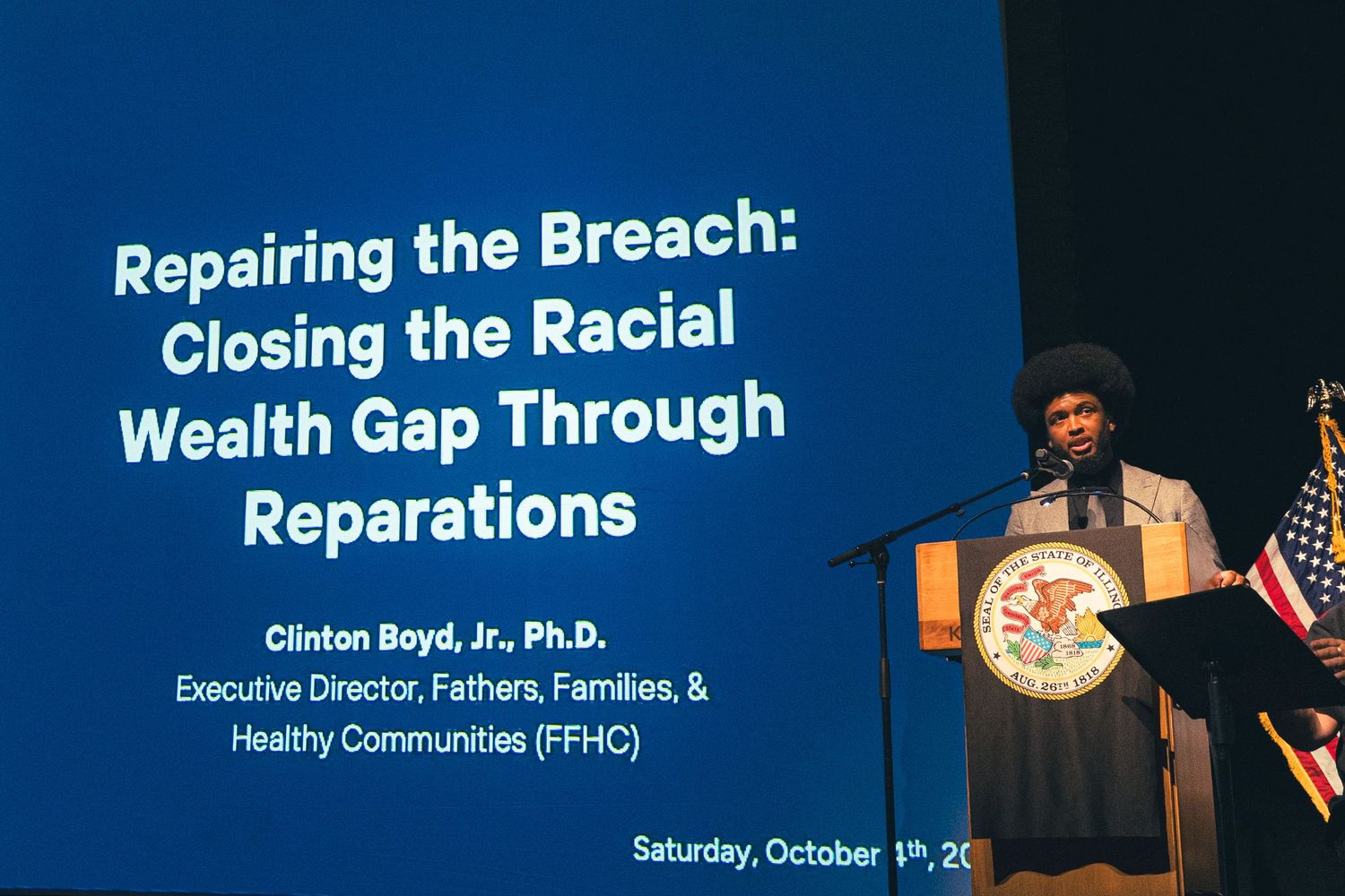 Dr. Clinton Boyd Jr. speaks at a podium presenting on Repairing the Breach and Closing the Racial Wealth Gap.