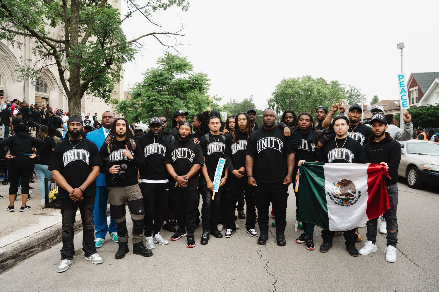 Large group of men in matching Unity shirts posing together at an outdoor community peace march.