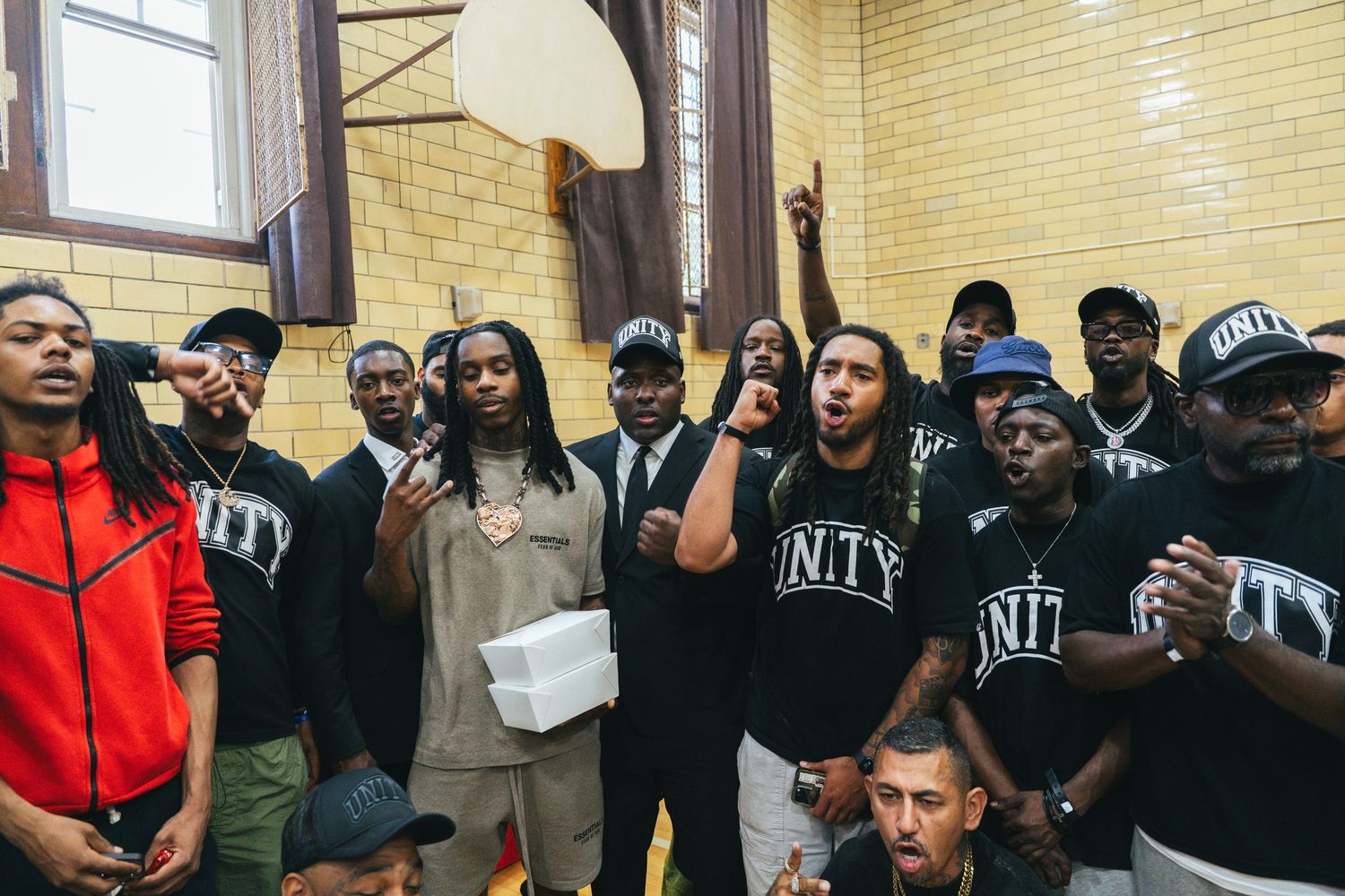 A group of people wearing black Unity shirts gather together in a school gymnasium for a community event.