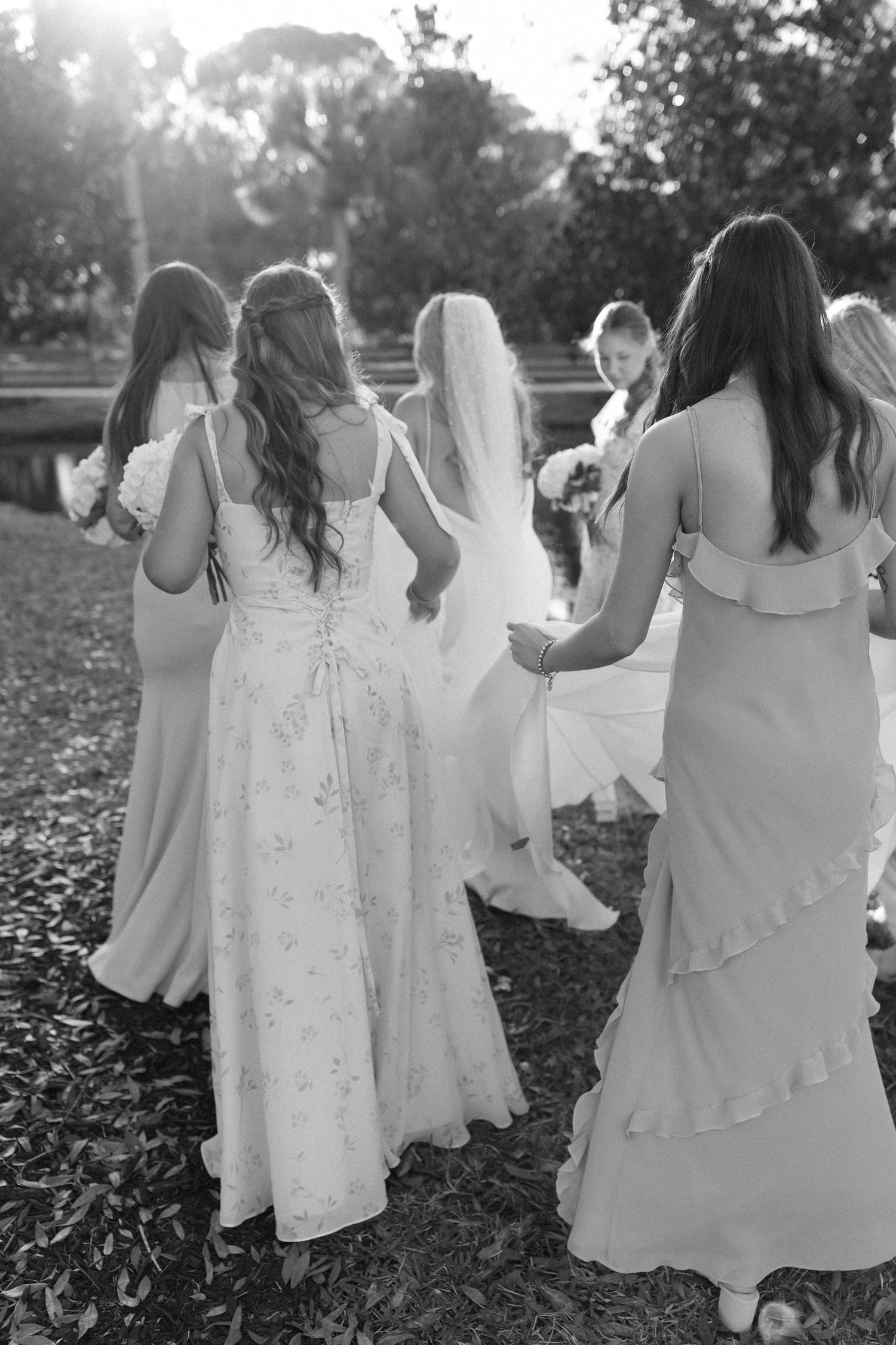 Close-up view of flowing white dresses as wedding party walks on fallen leaves.