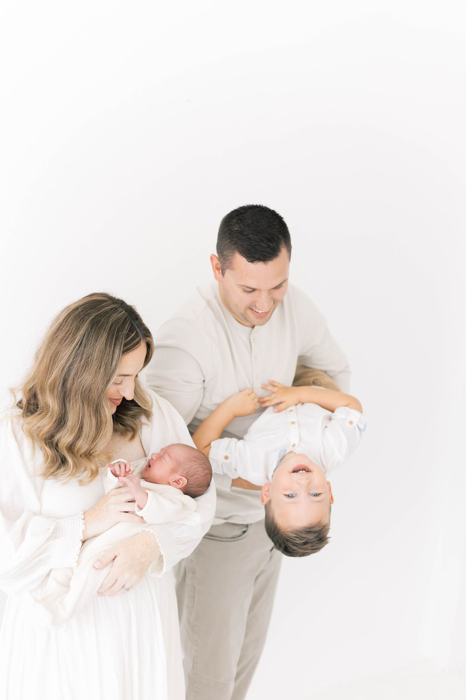Intimate family portraits showing tender moments with children in minimalist white setting.