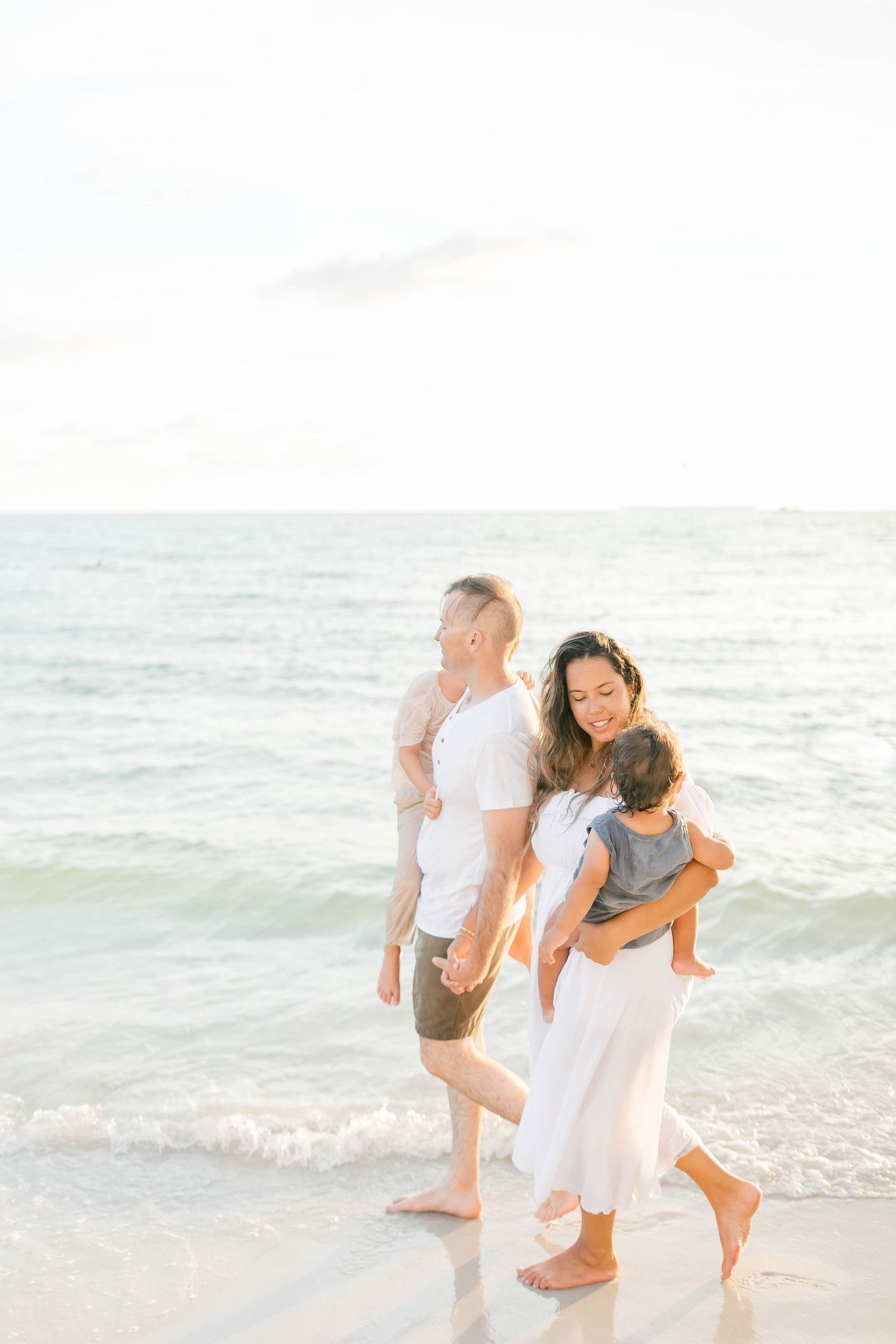 Joyful family moment captured in soft lighting on a peaceful beach.